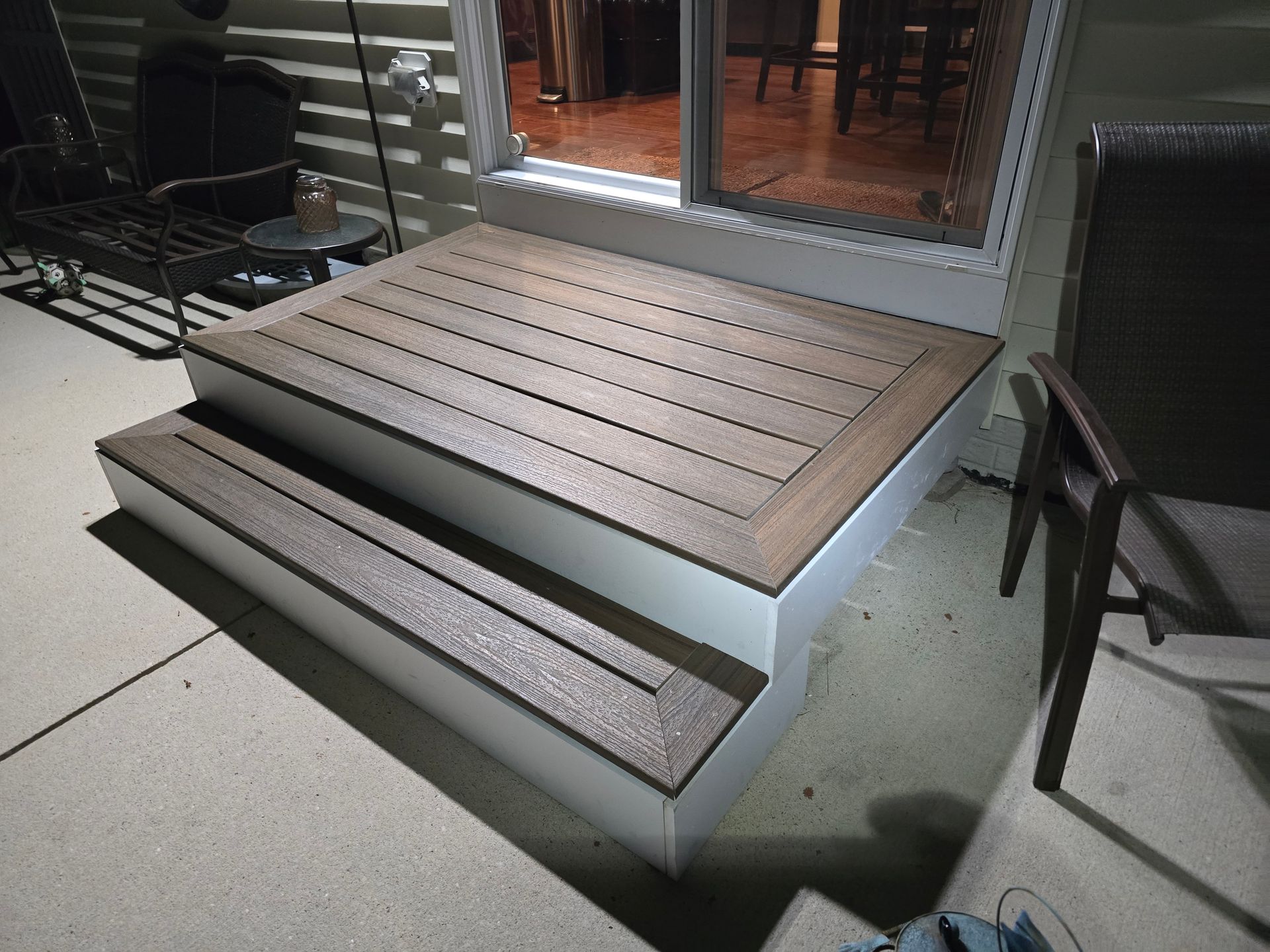 A set of wooden steps leading up to a sliding glass door