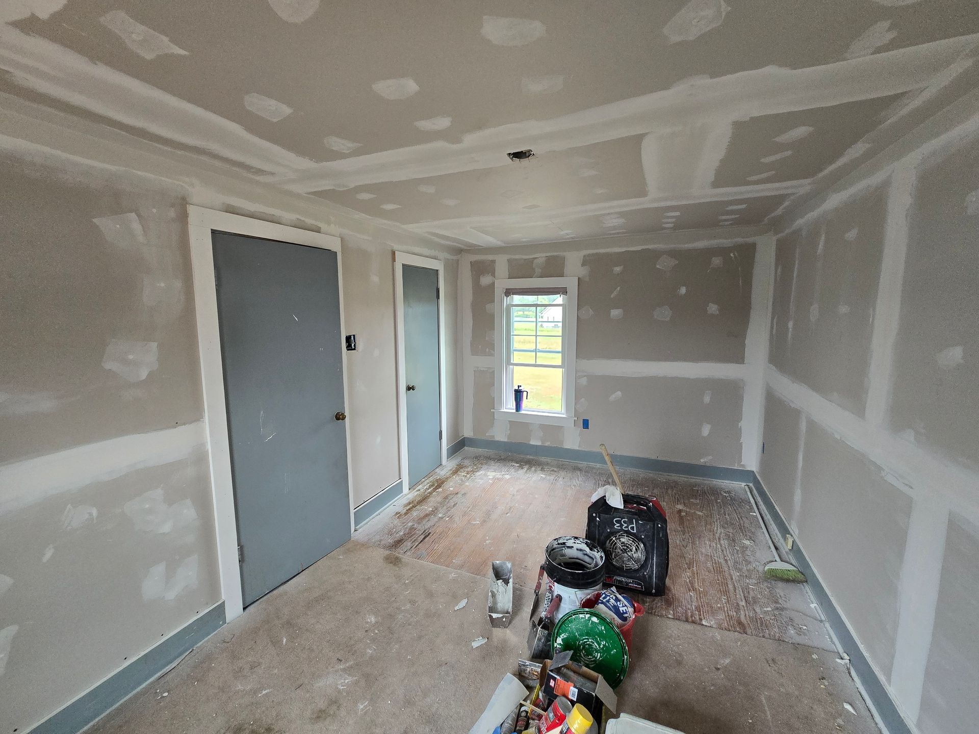 A room with drywall on the walls and a window.