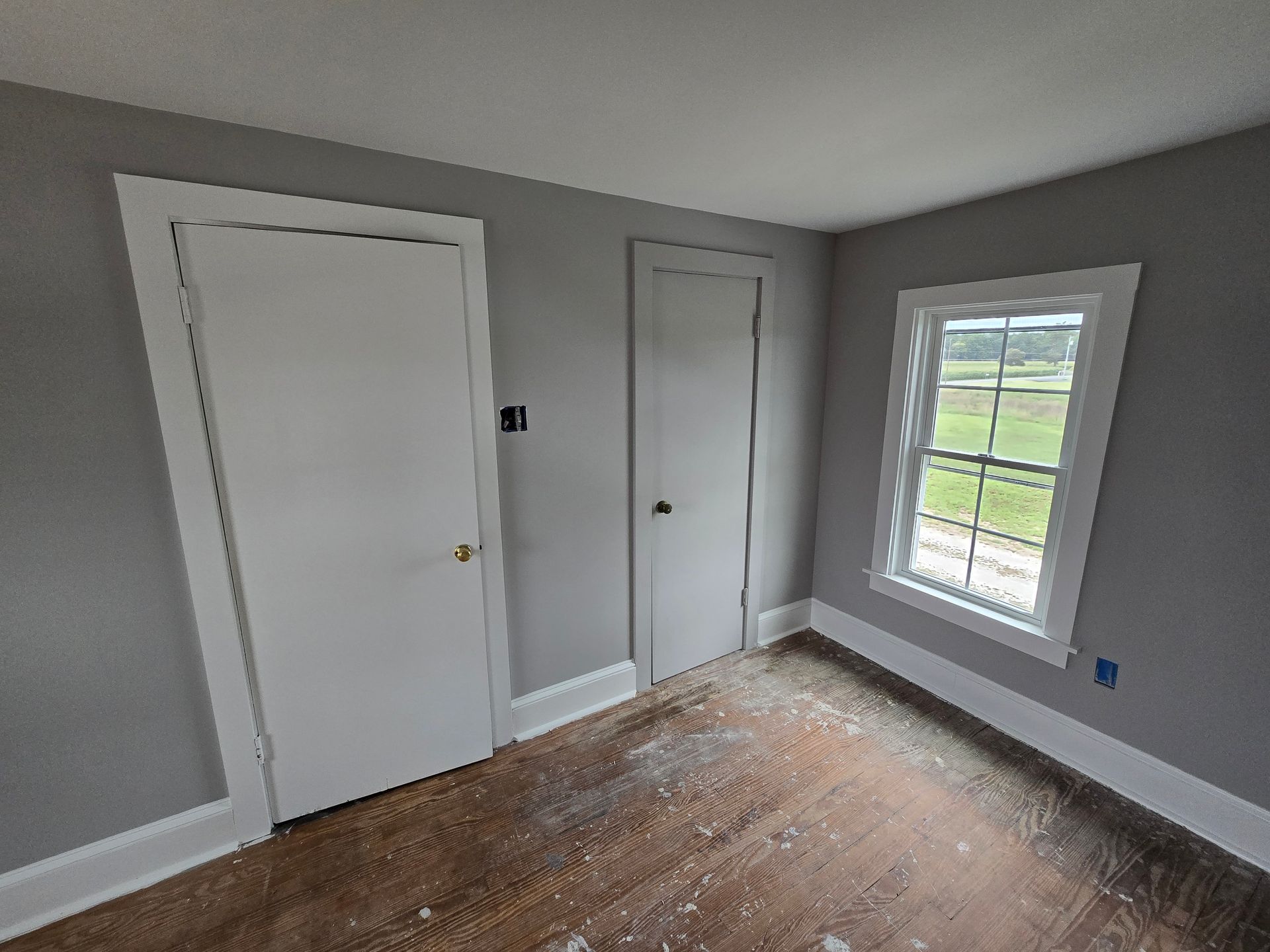 An empty room with two doors and a window.