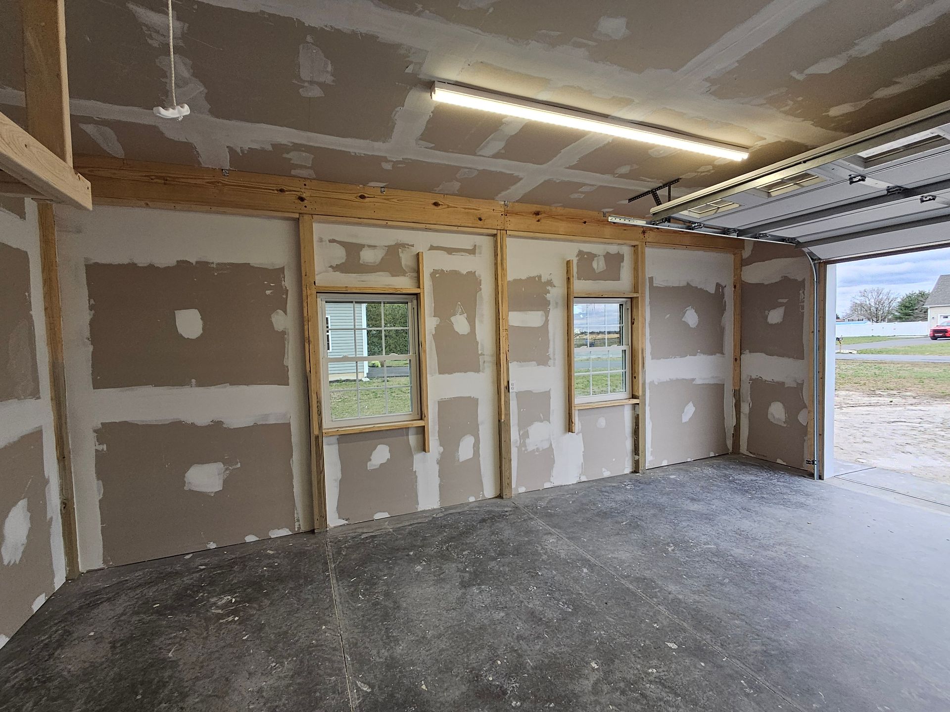 An empty garage with drywall walls and a garage door