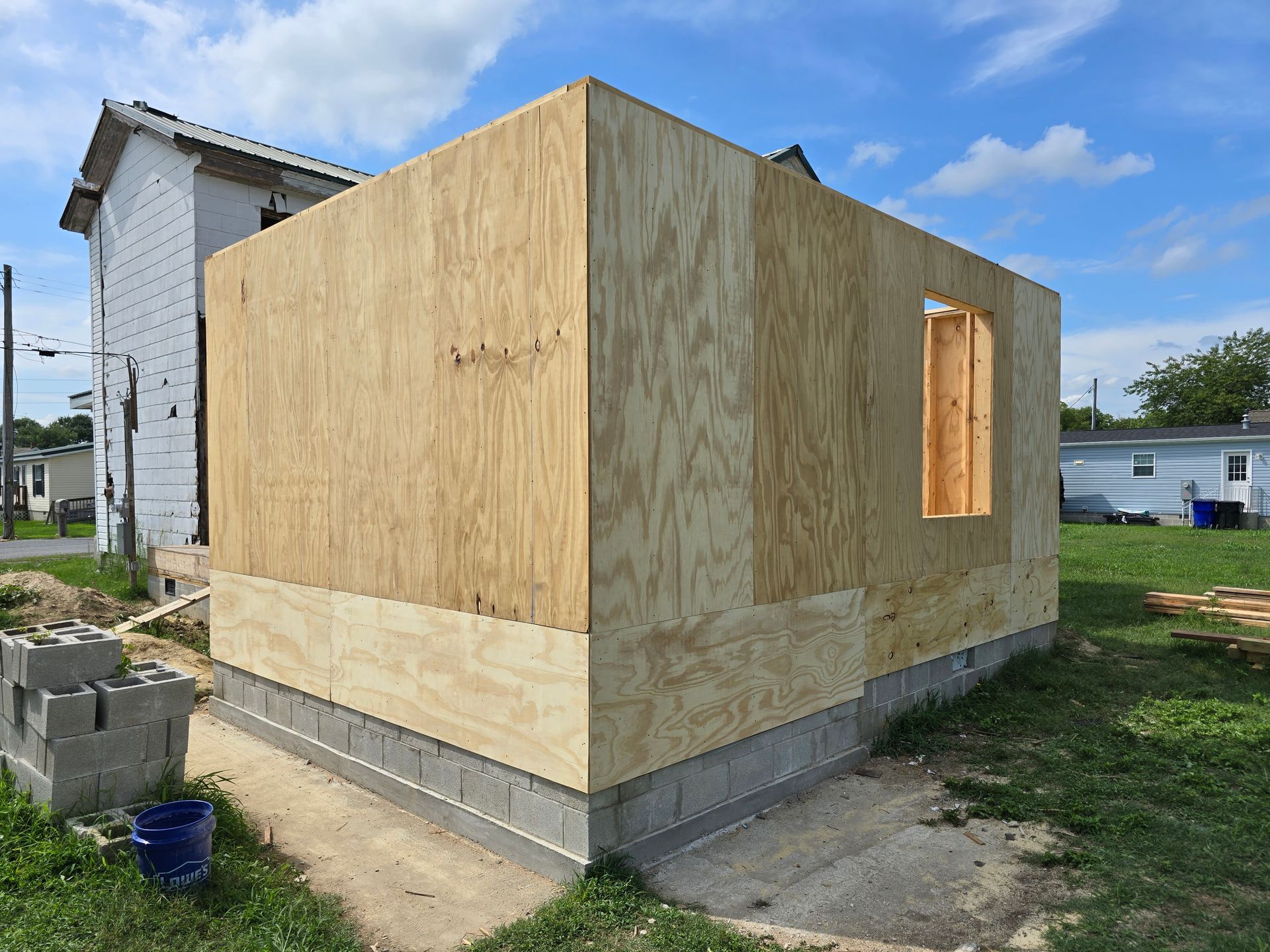 A small wooden building is being built in the backyard of a house.
