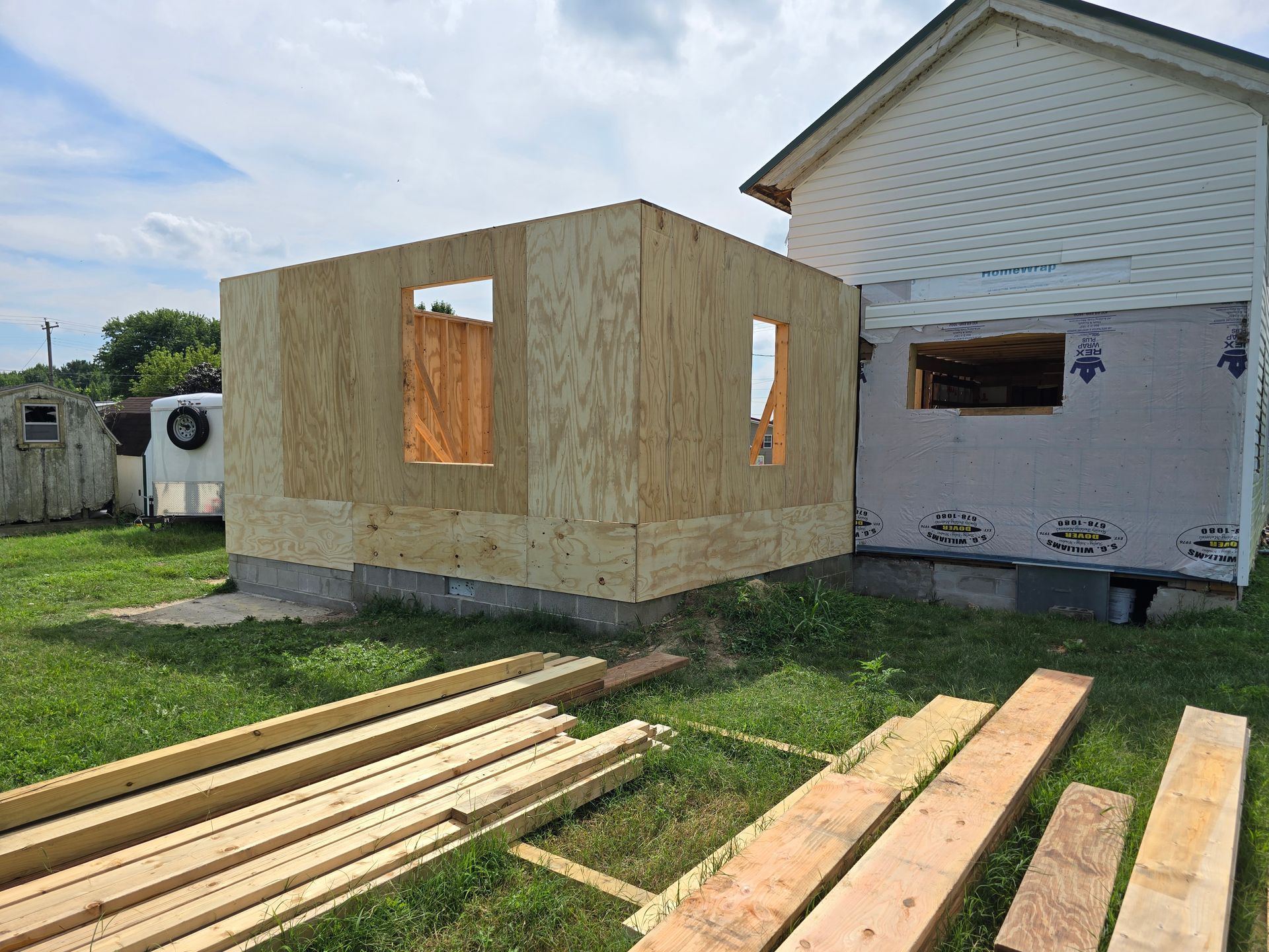 A house under construction with a lot of wood in front of it.