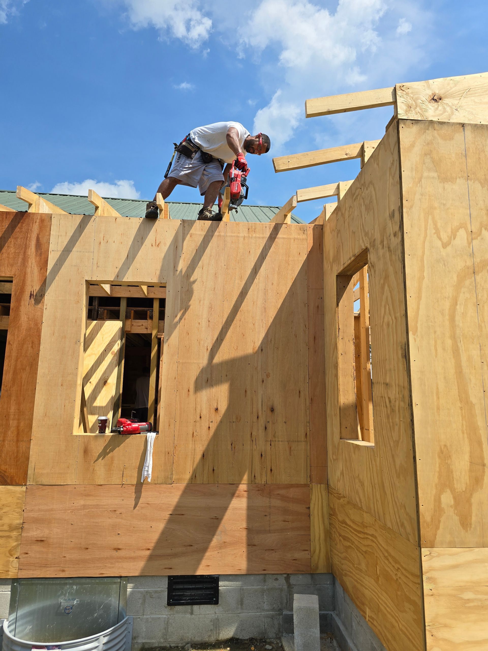 A man is working on the roof of a house under construction