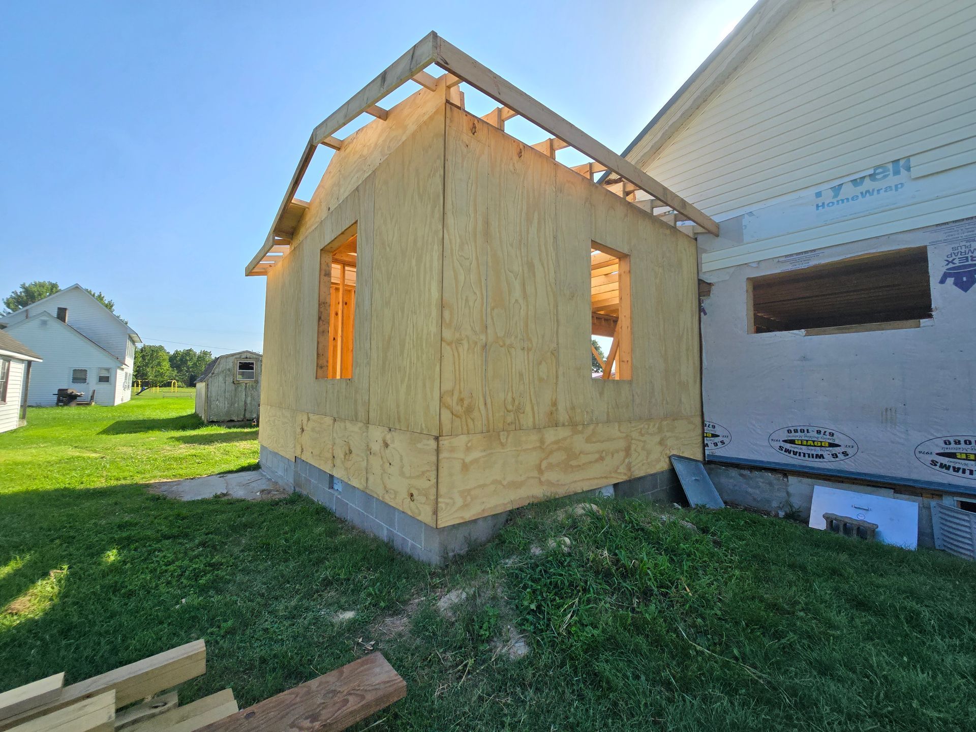 A small wooden house is being built in the backyard of a house.