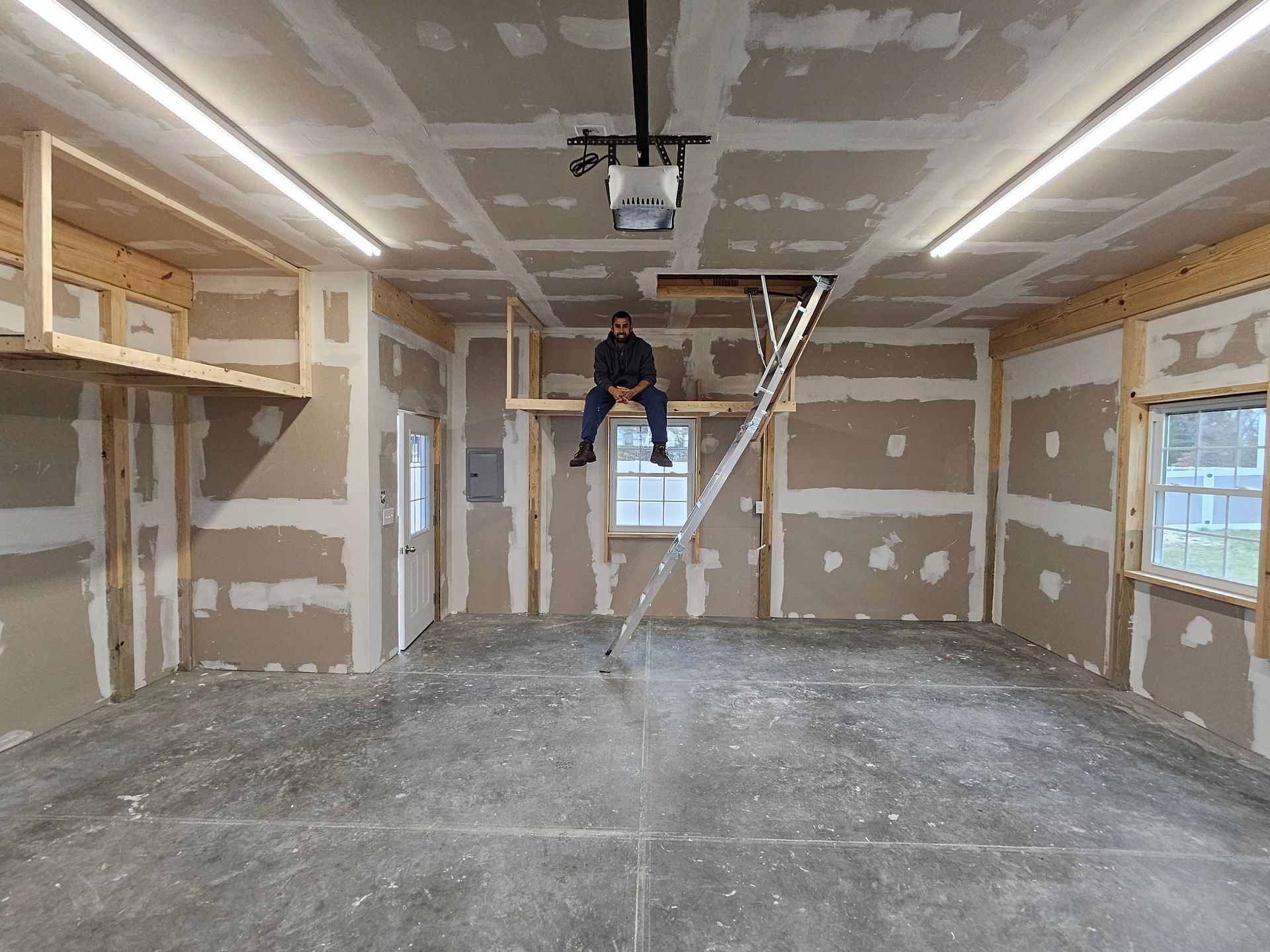 A man is sitting on a ladder in a garage.