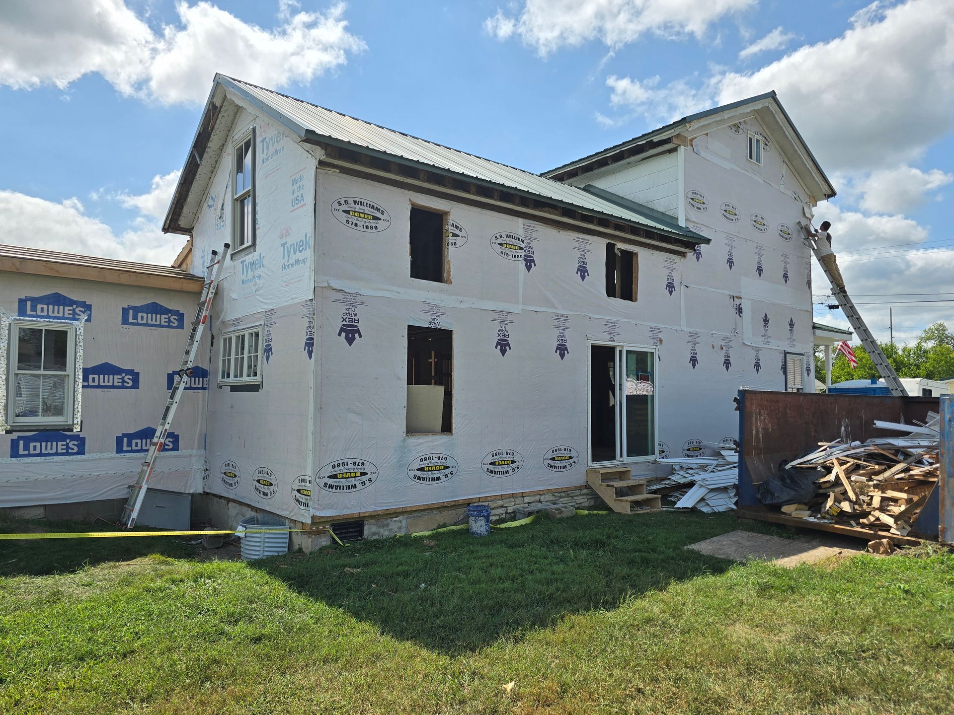 A large white house is being built in the middle of a grassy field.