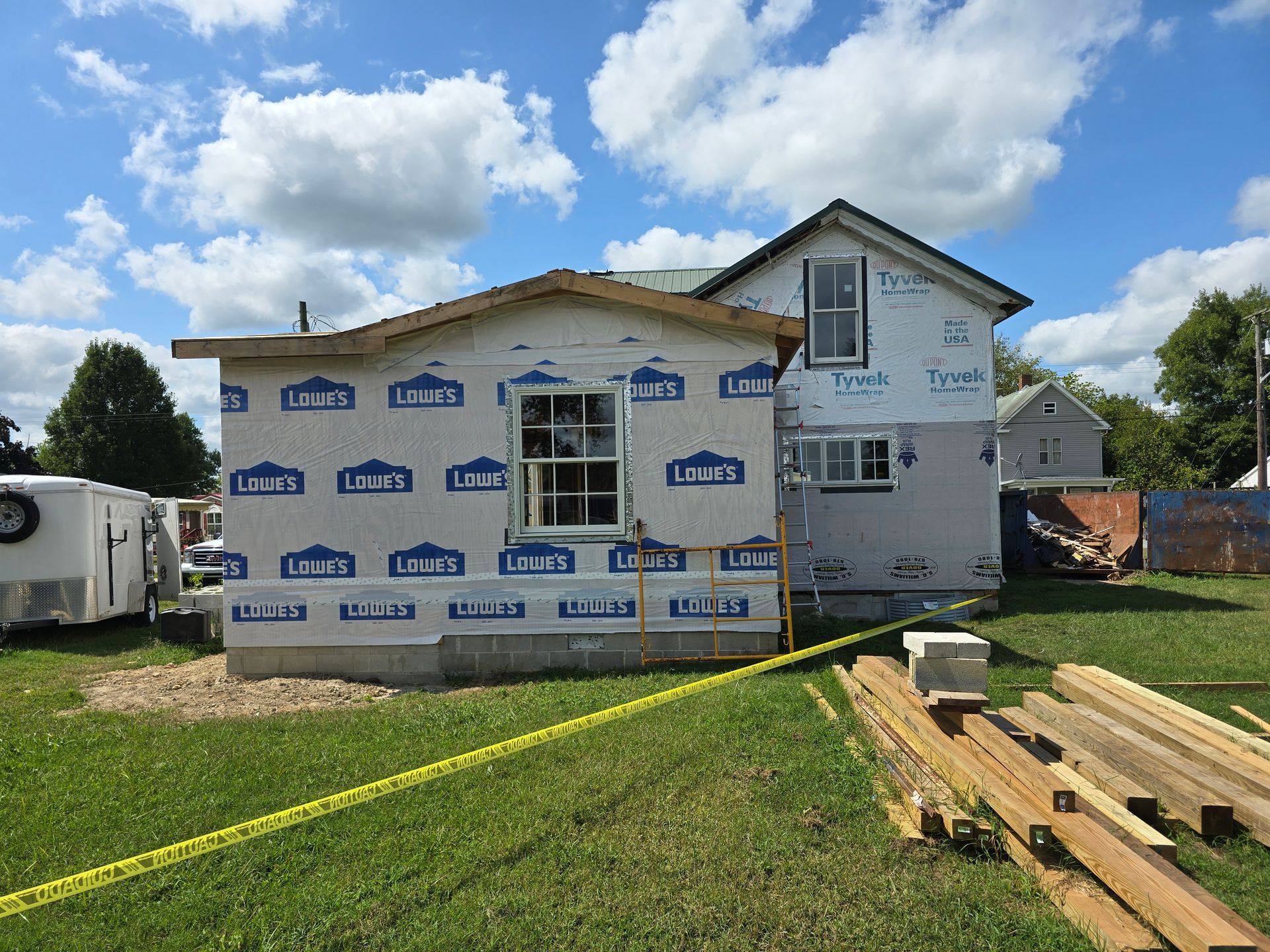 A house is being built with a lot of wood in front of it.