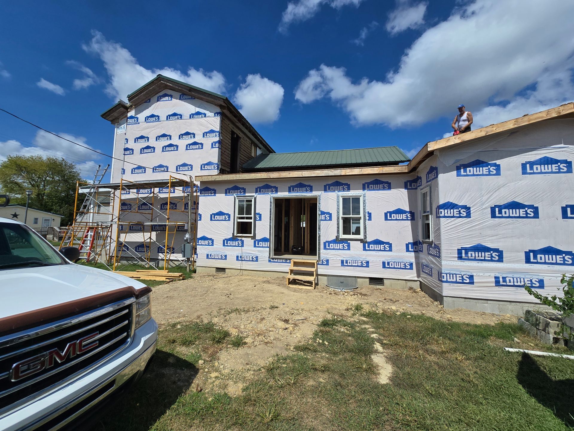 A gmc truck is parked in front of a house under construction.