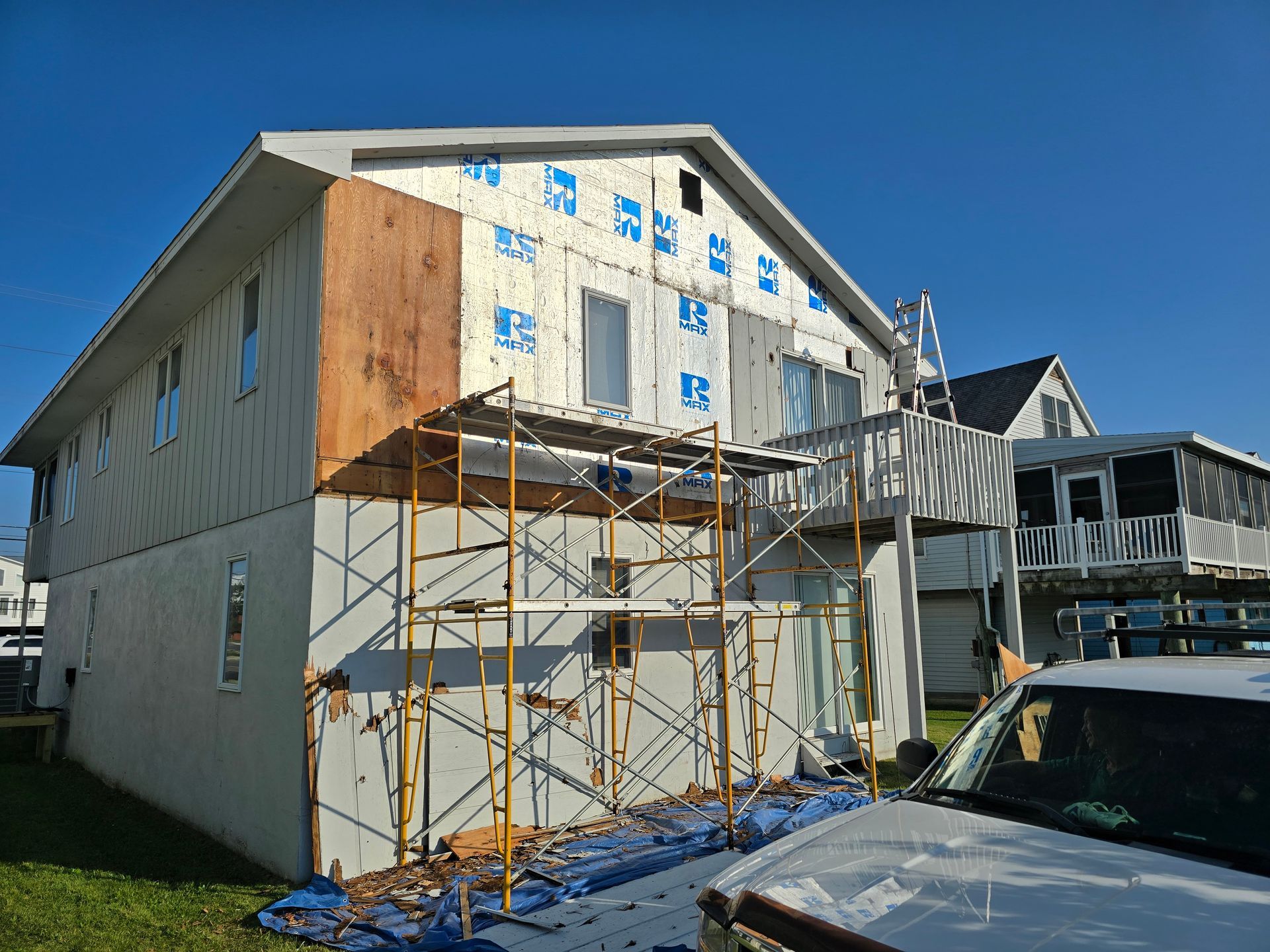 A house is being remodeled with scaffolding and a truck parked in front of it.
