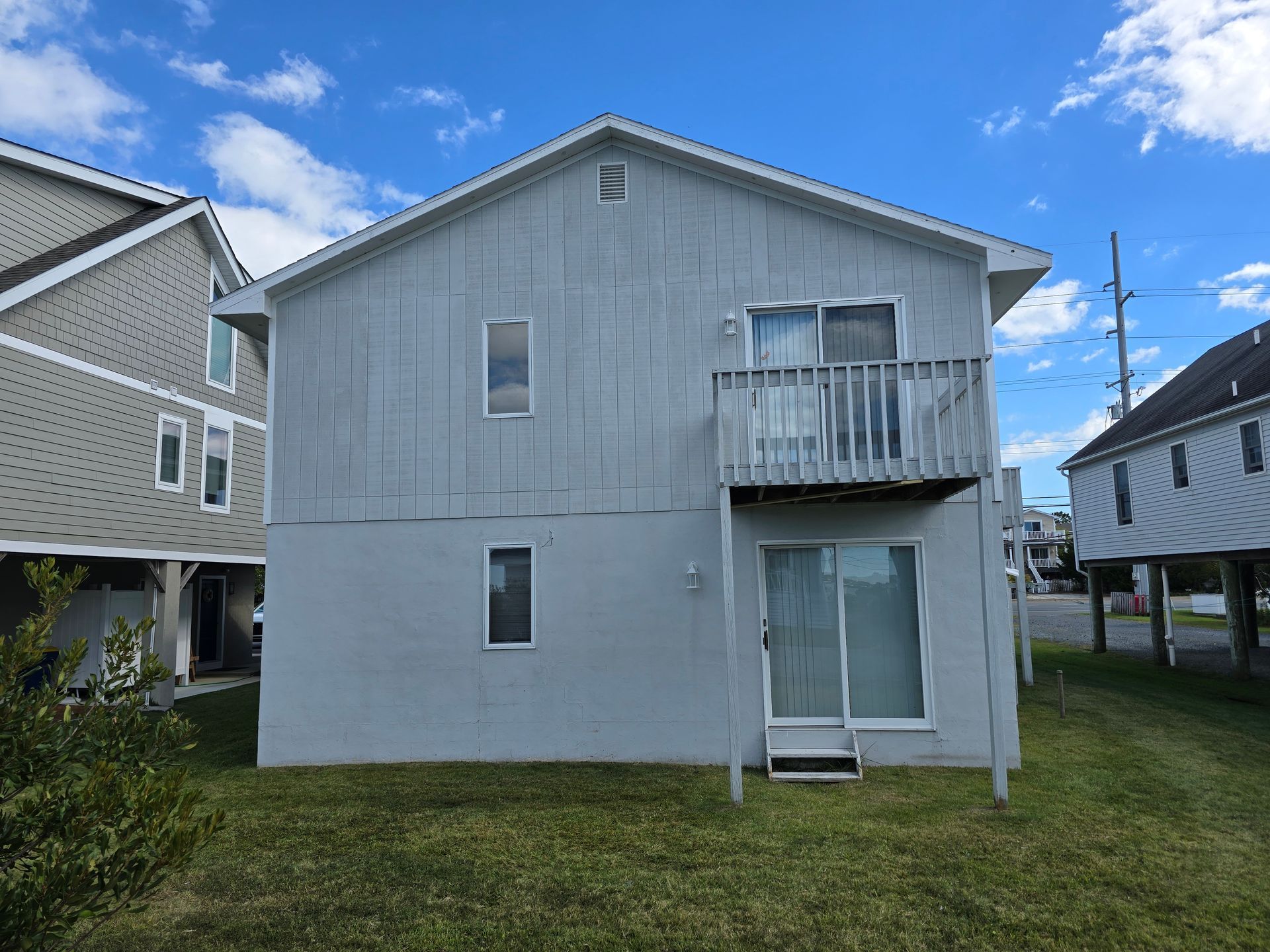 The back of a white house with a balcony and sliding glass doors.