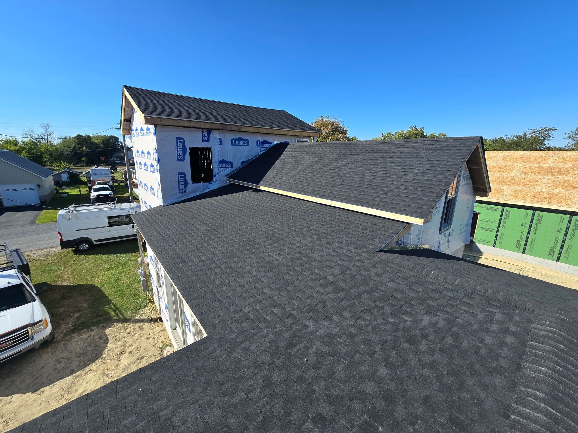 A house under construction with a black roof and a white van parked in front of it.