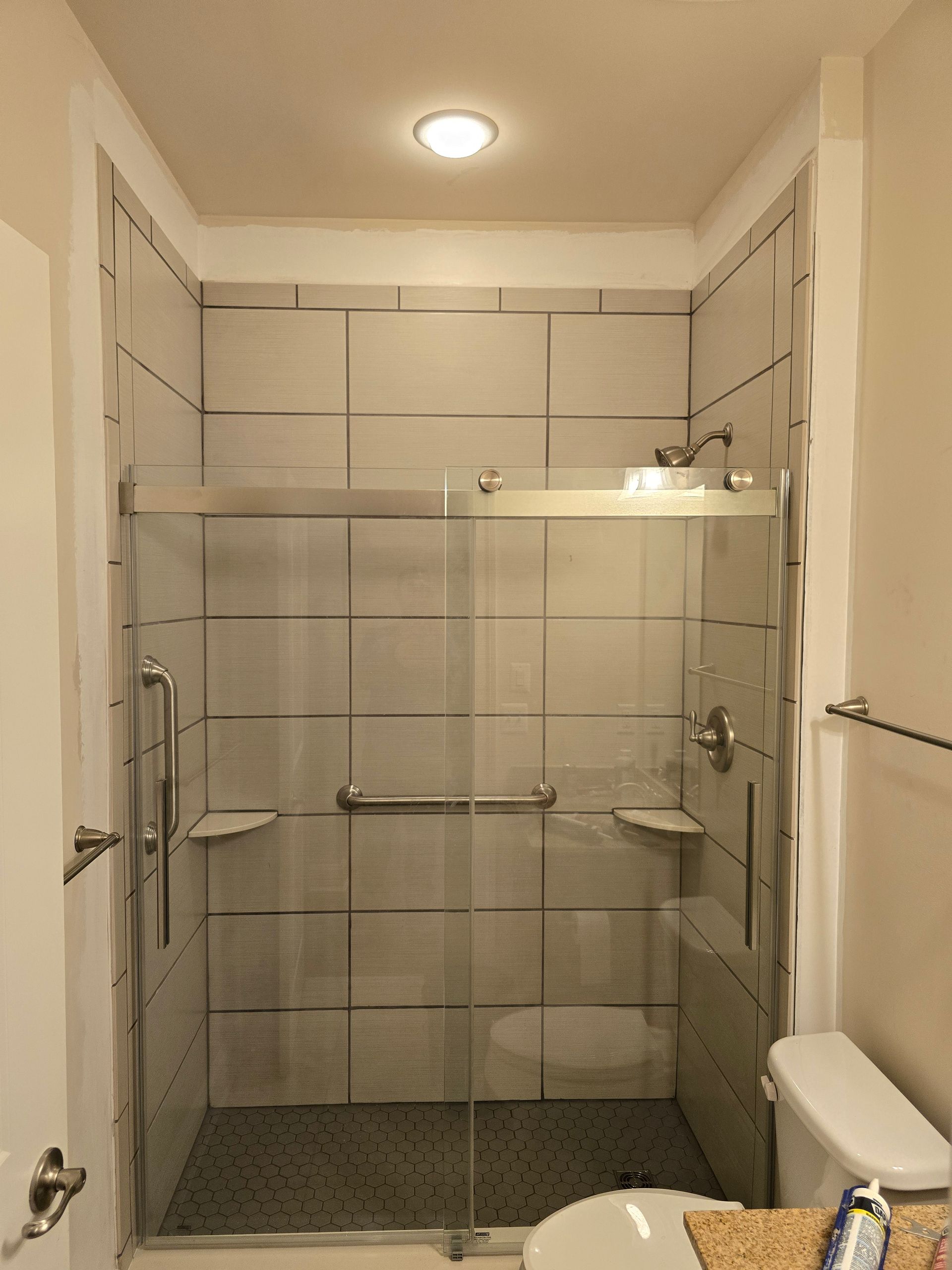 A bathroom with a sliding glass shower door and a toilet