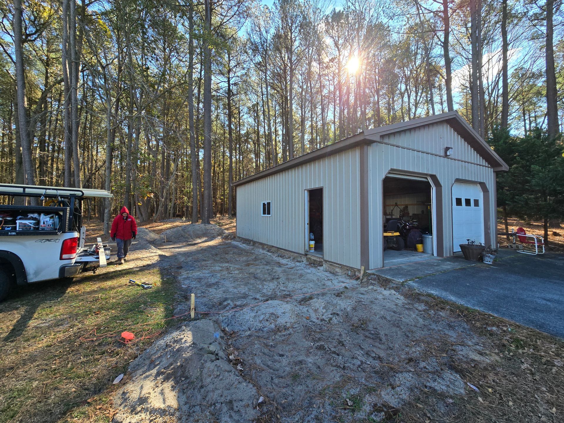 A truck is parked in front of a garage in the woods.
