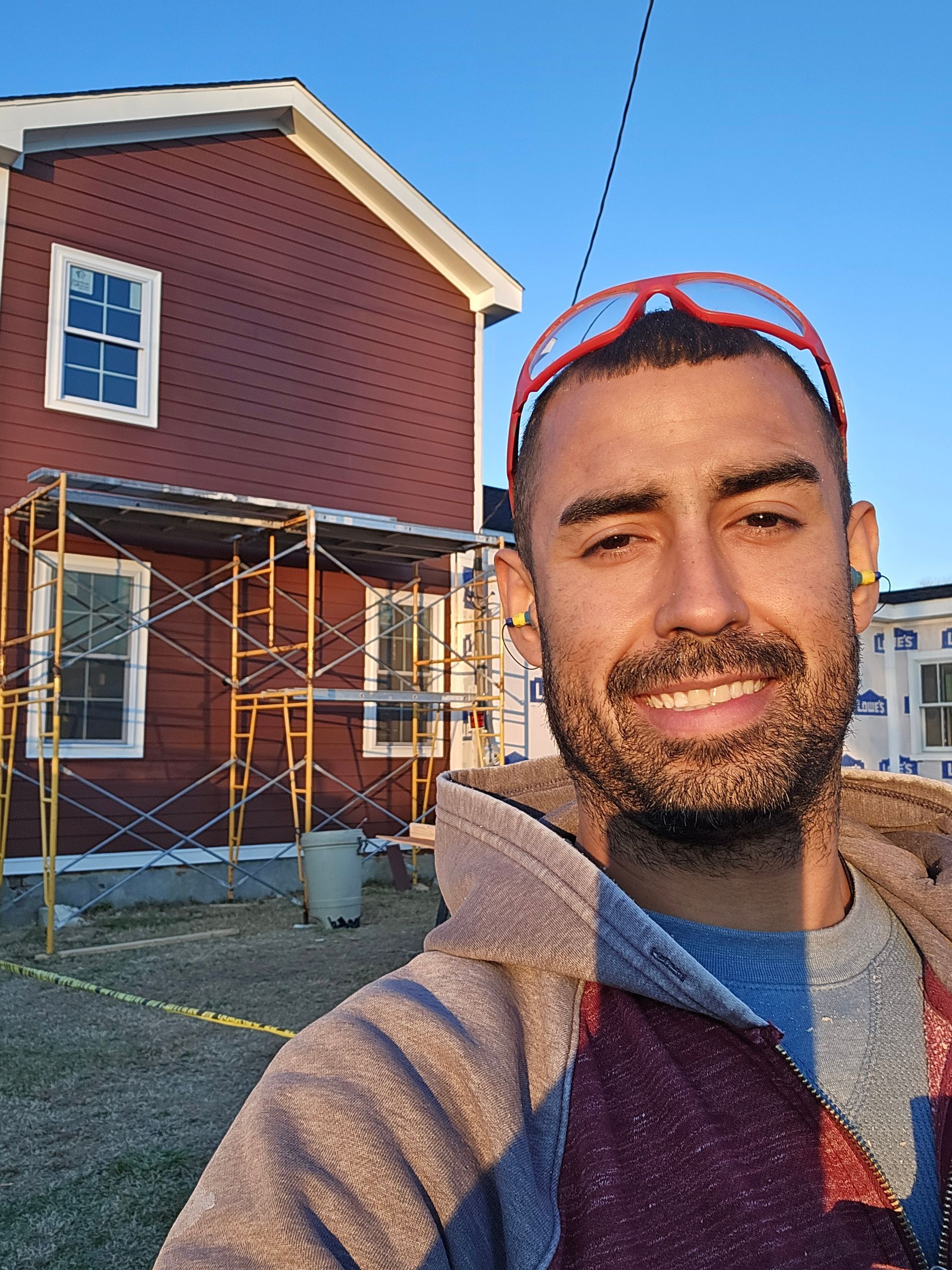 A man is taking a selfie in front of a house under construction.