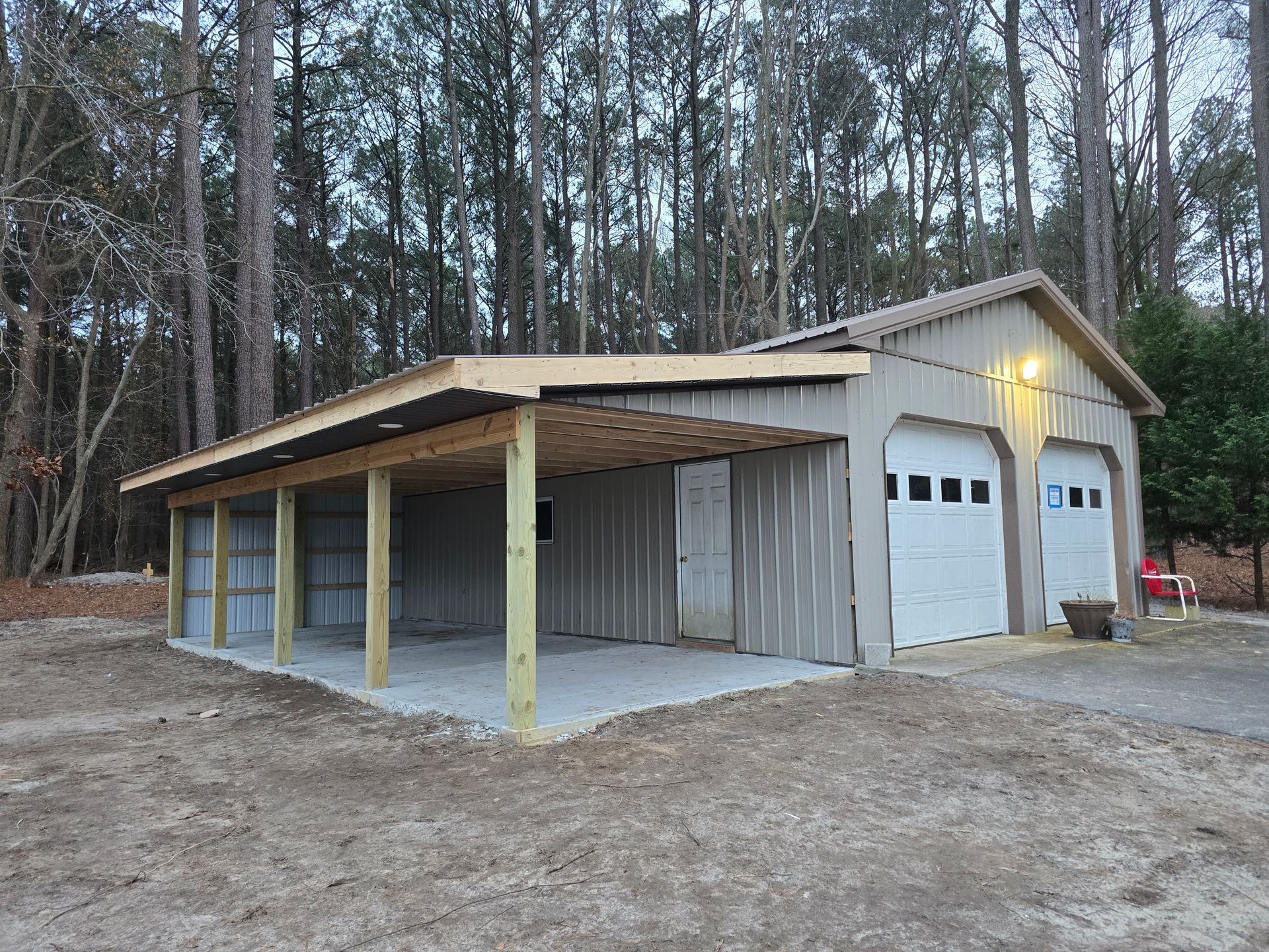 A garage with a covered area underneath it is surrounded by trees.