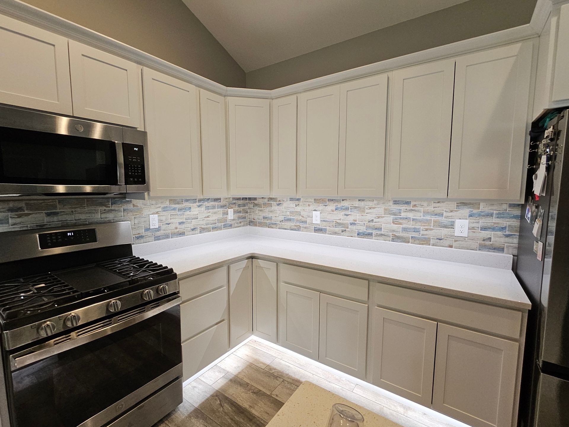 A kitchen with white cabinets , stainless steel appliances , and a stove.