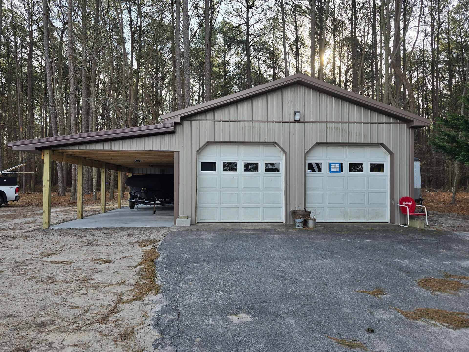 A garage with two garage doors and a carport underneath it.