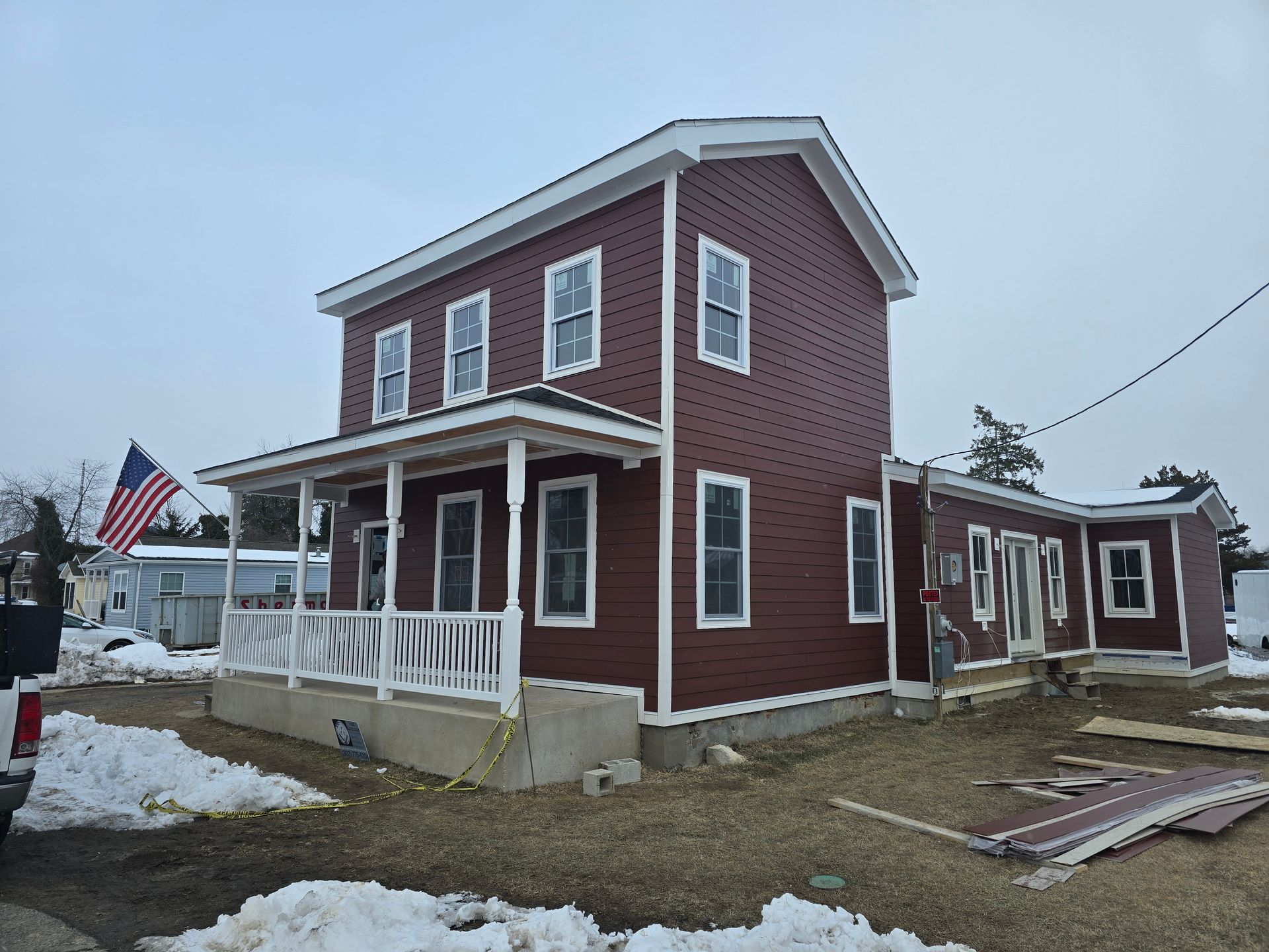 A red house with a white porch and an american flag