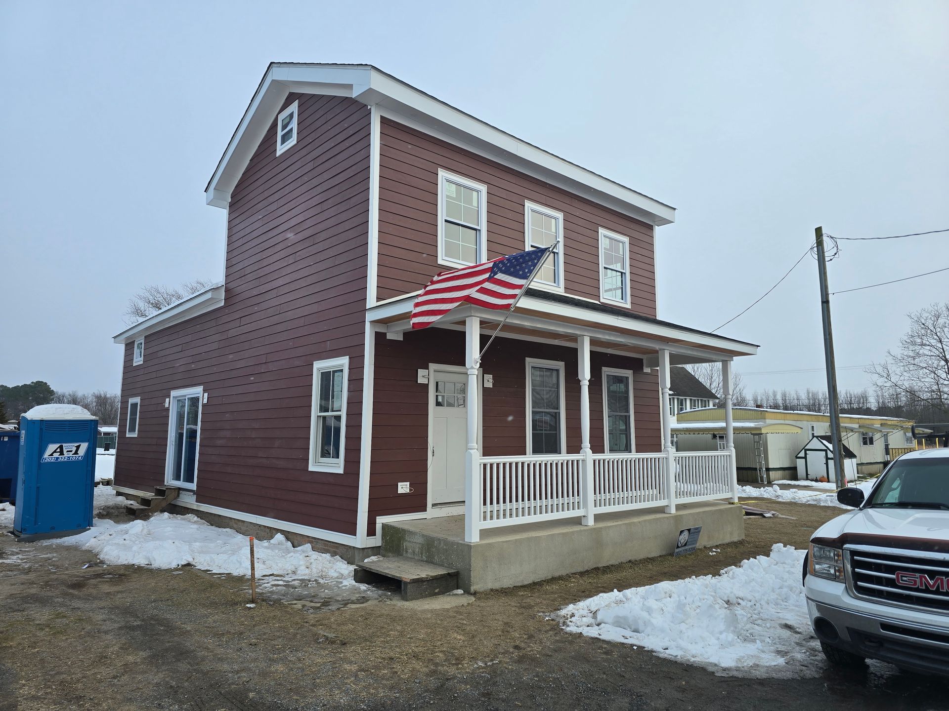 A red house with an american flag on the front porch.