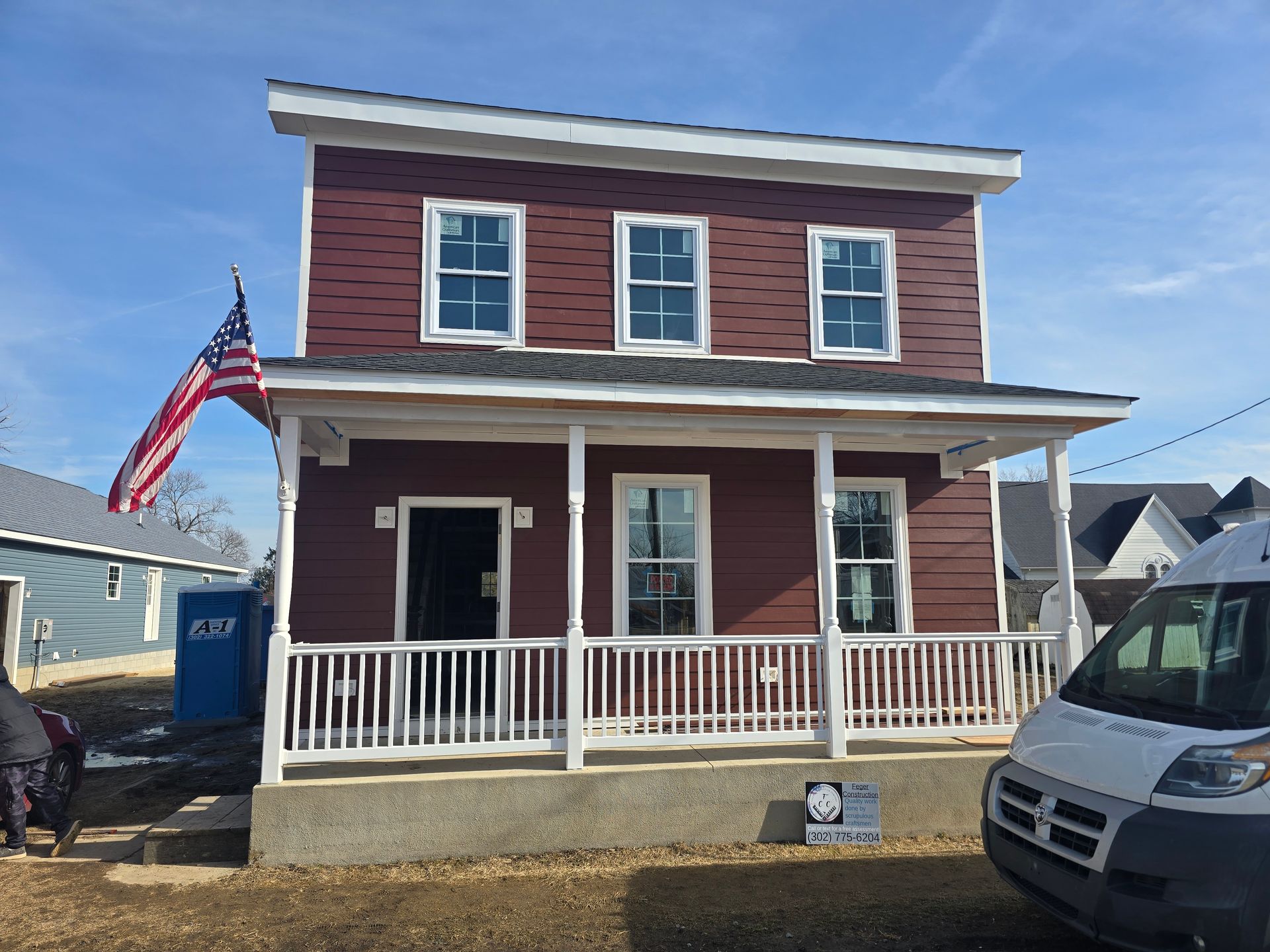 A red house with a white van parked in front of it.