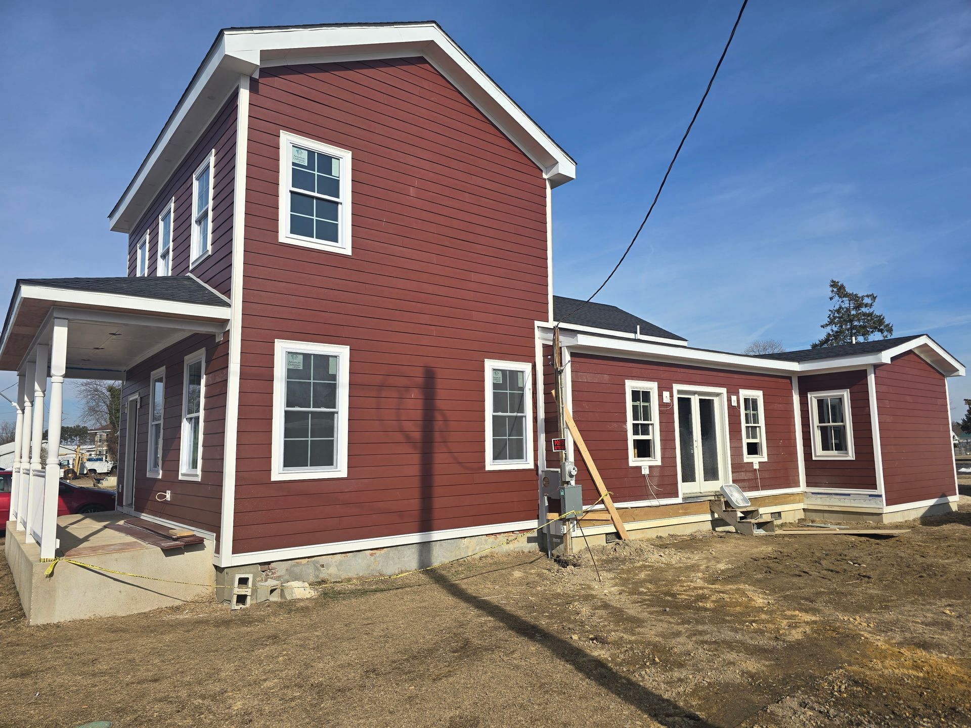 A large red house with white trim is being built