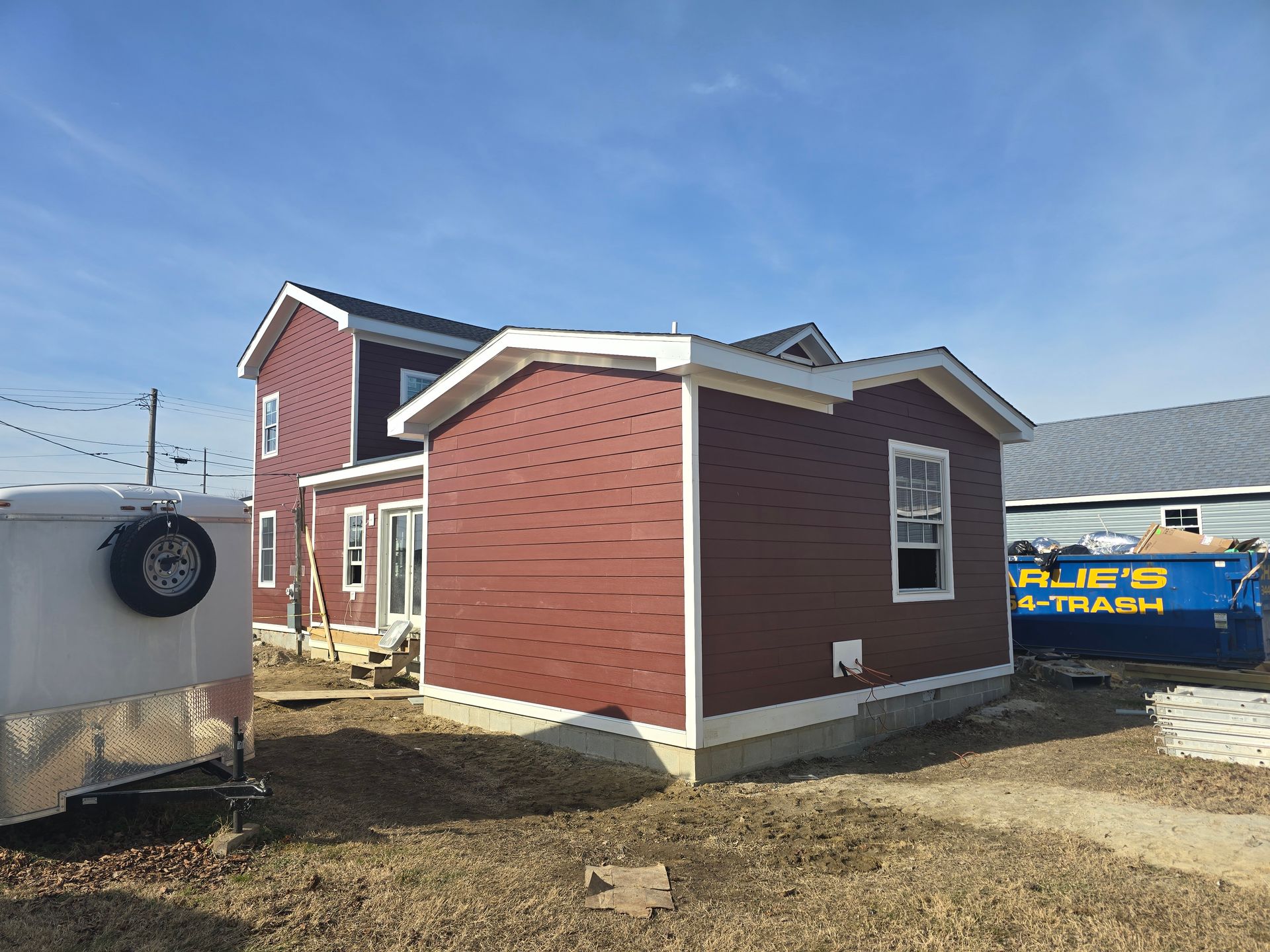 A small red house is being built next to a large house.