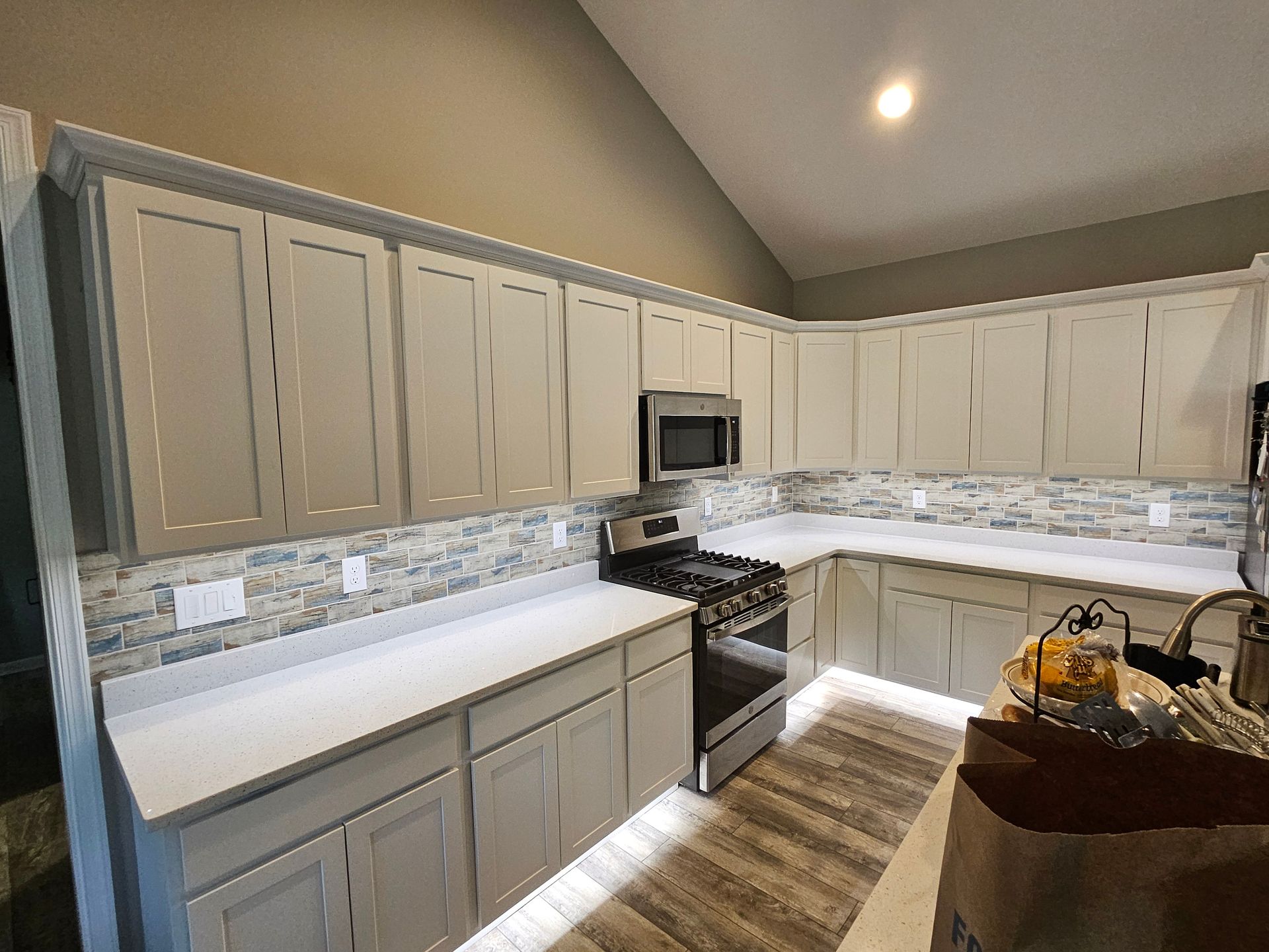 A kitchen with a stove , microwave , refrigerator and cabinets.