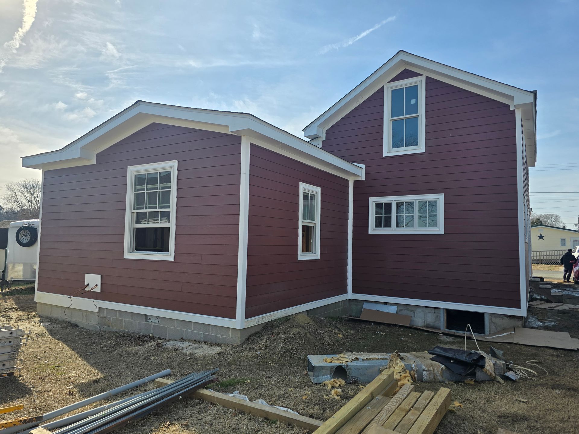 A red house with white trim and windows is being built.