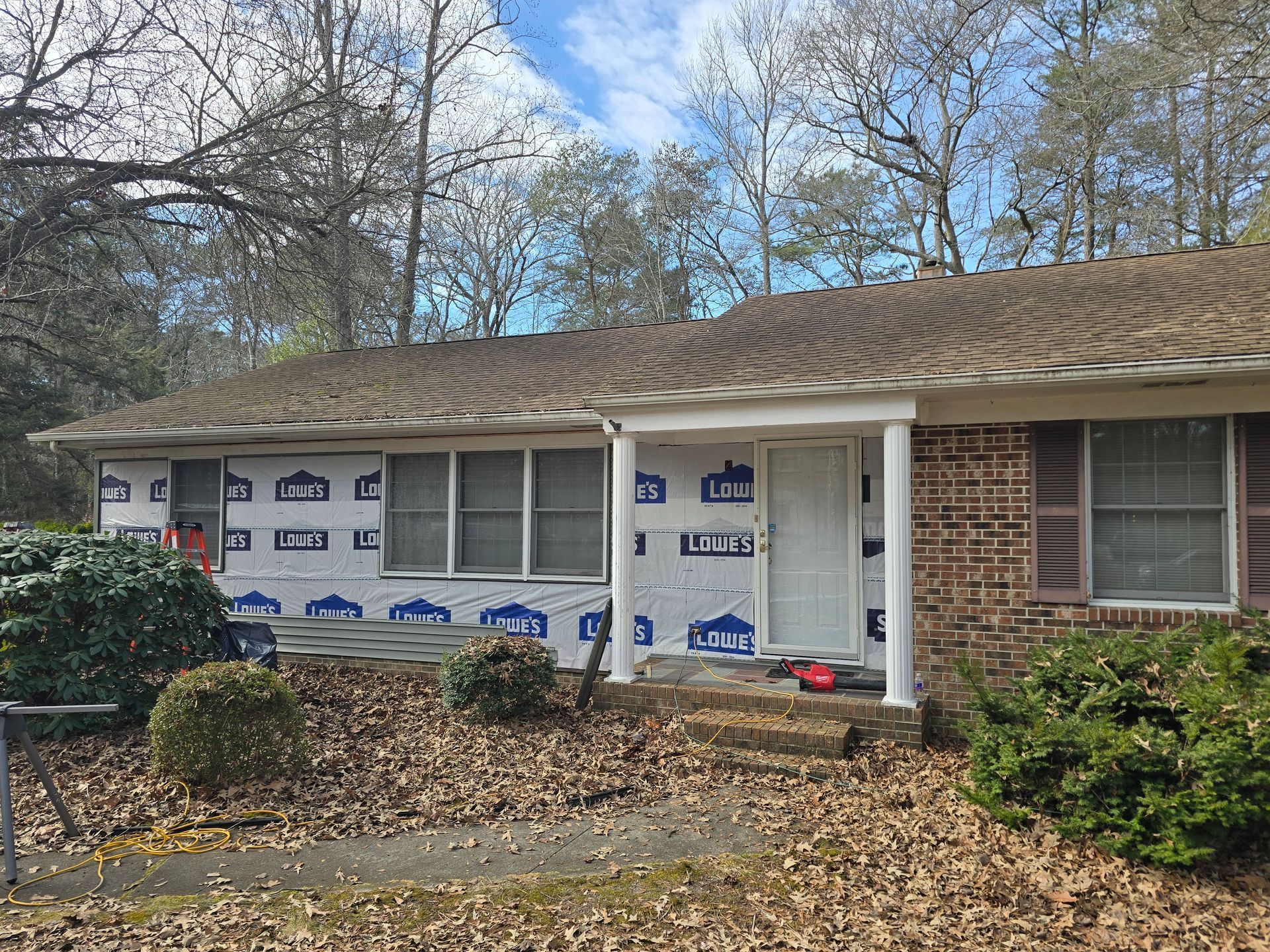 A brick house with a porch and a roof is being remodeled.