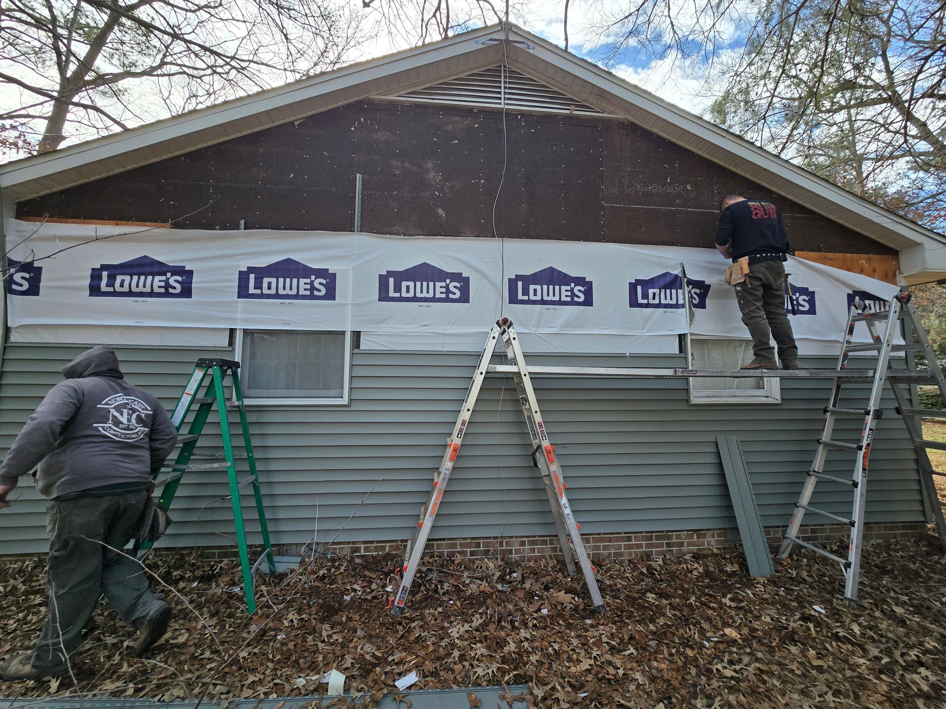 A couple of men are working on the side of a house.