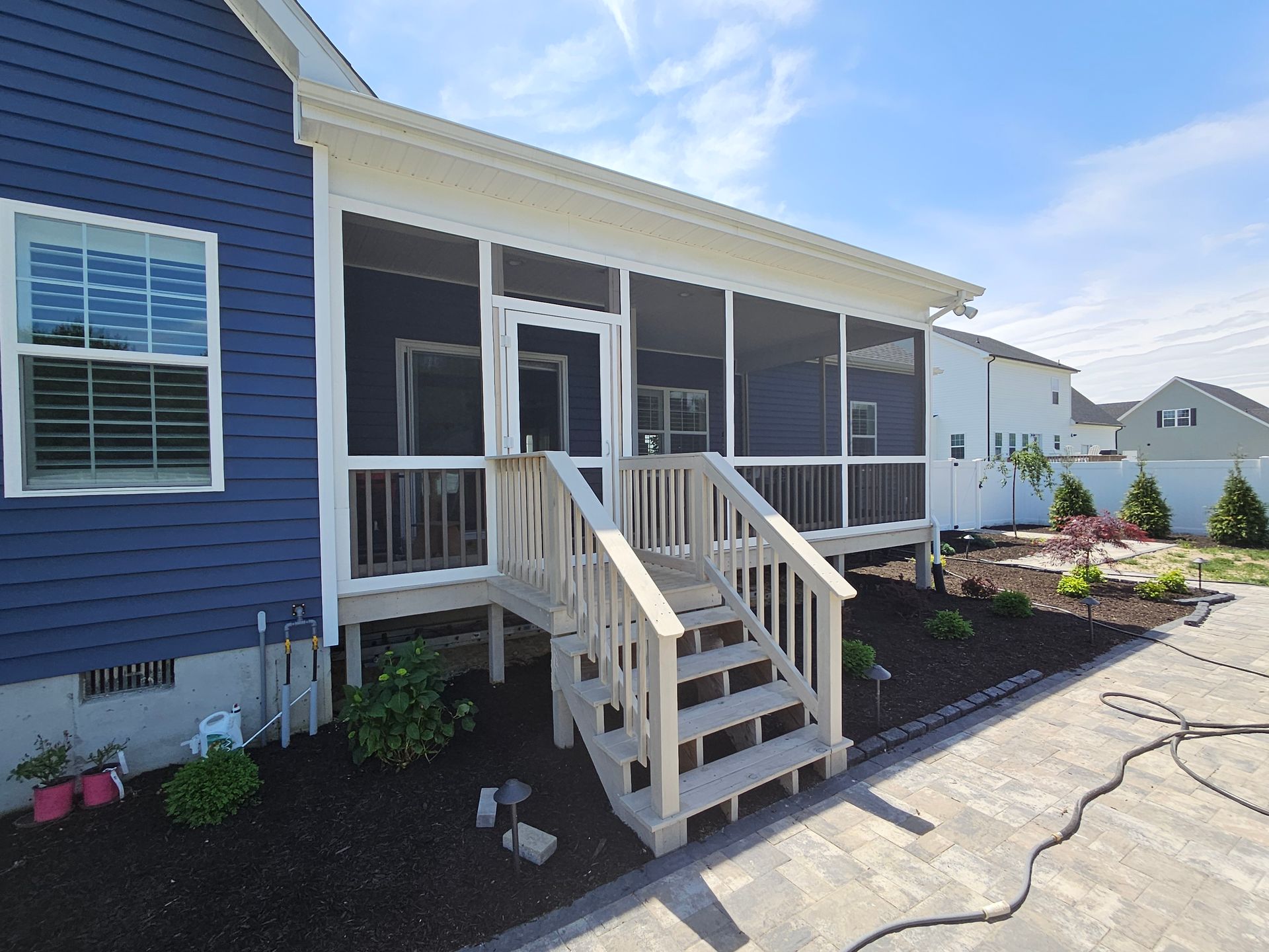 A blue house with a screened in porch and stairs.