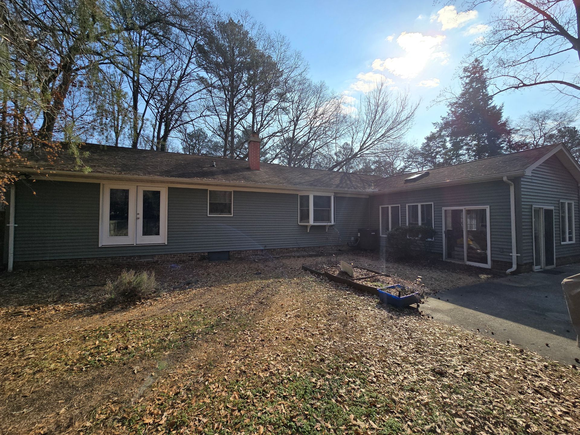 A house with a lot of leaves on the ground in front of it.