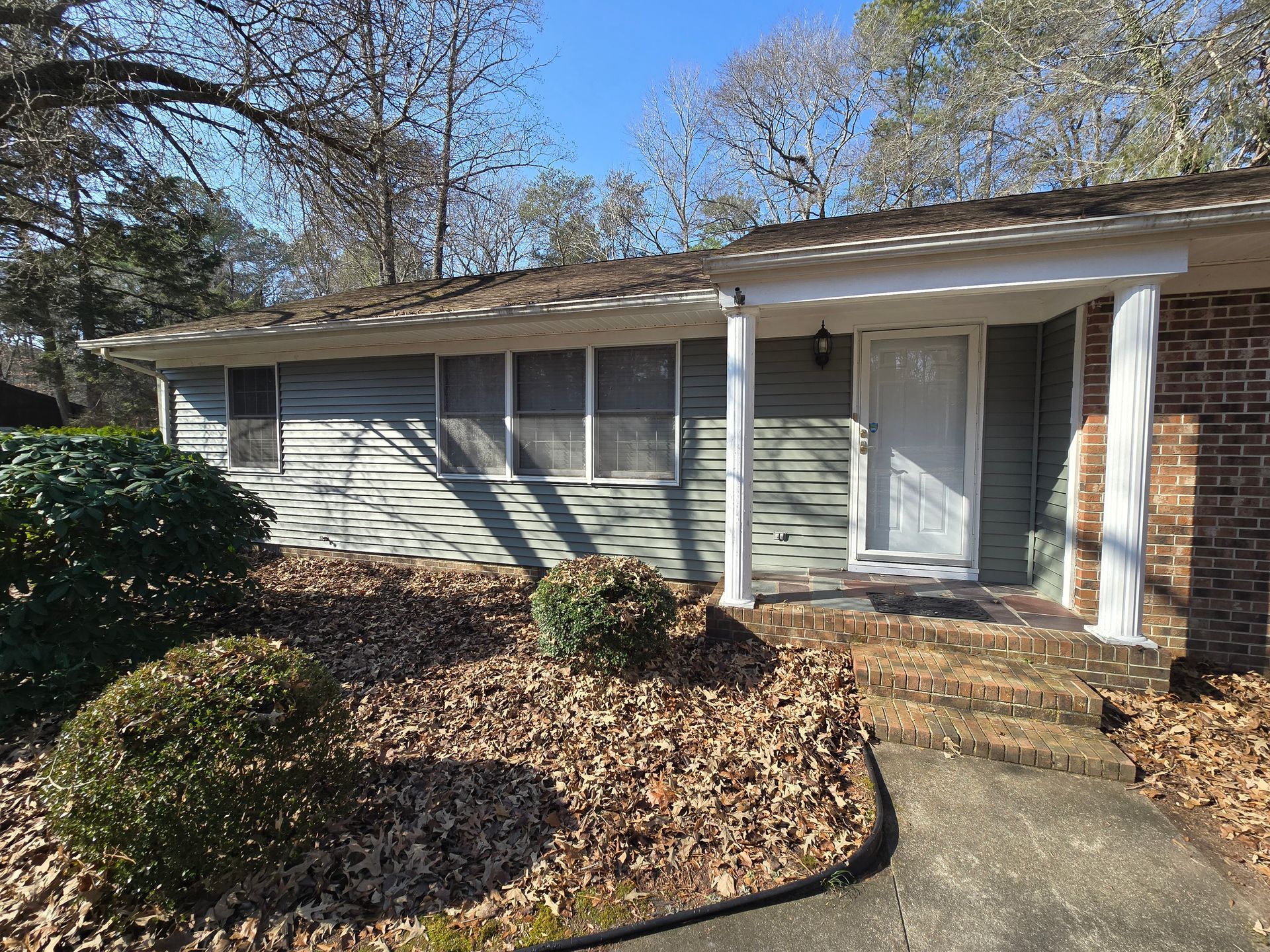 A house with a porch and a lot of leaves on the ground.