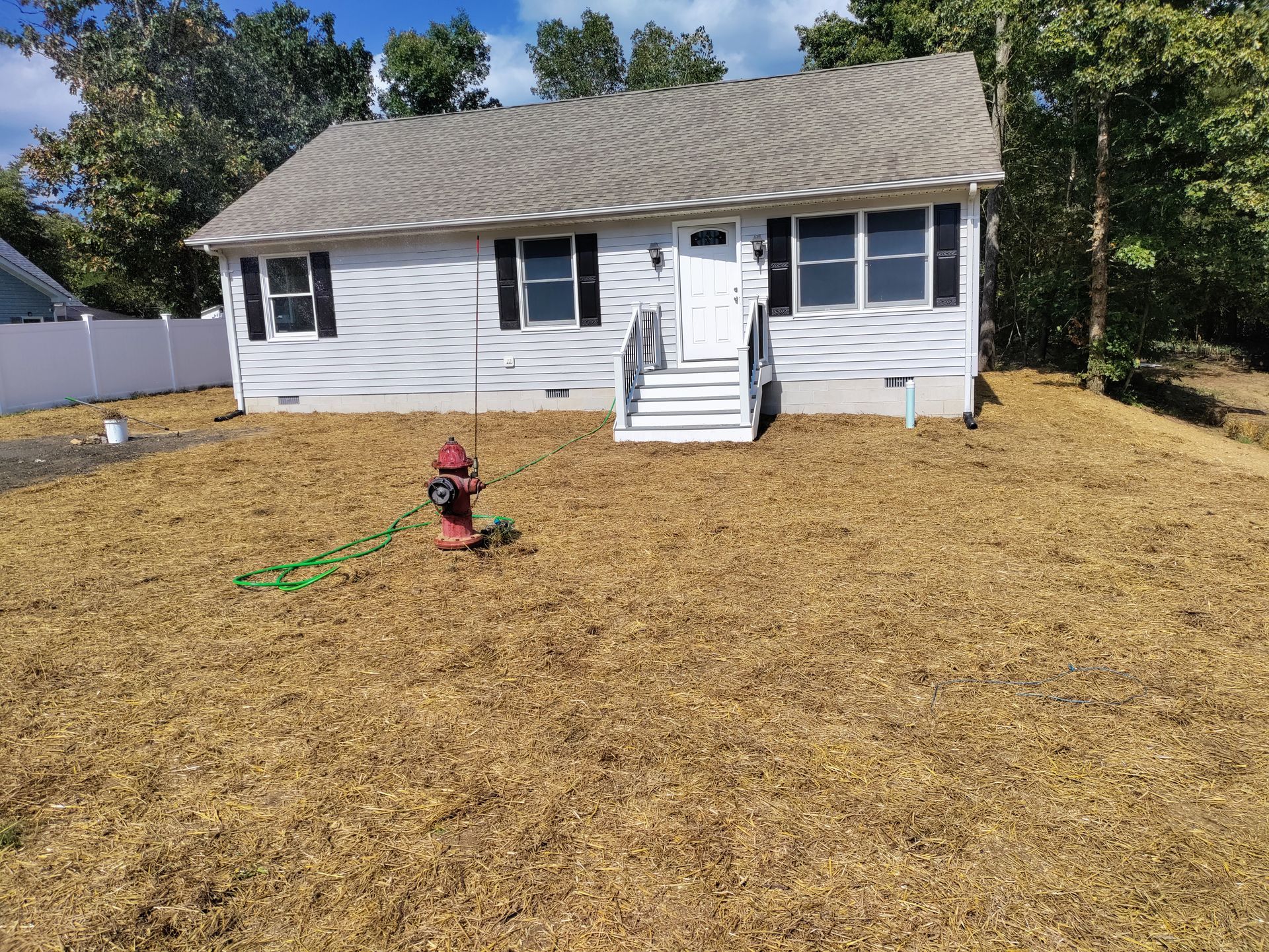 A white house with a fire hydrant in front of it.