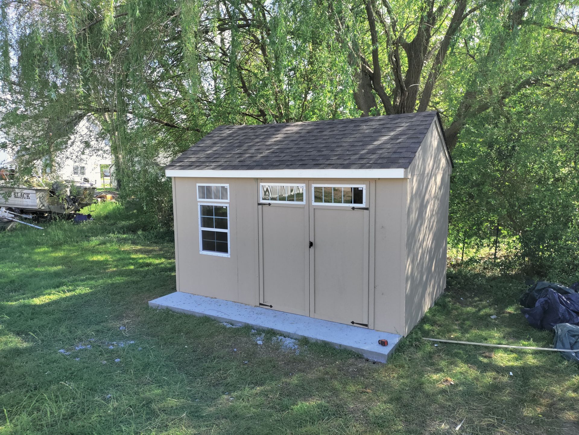 A small shed is sitting in the middle of a lush green field.