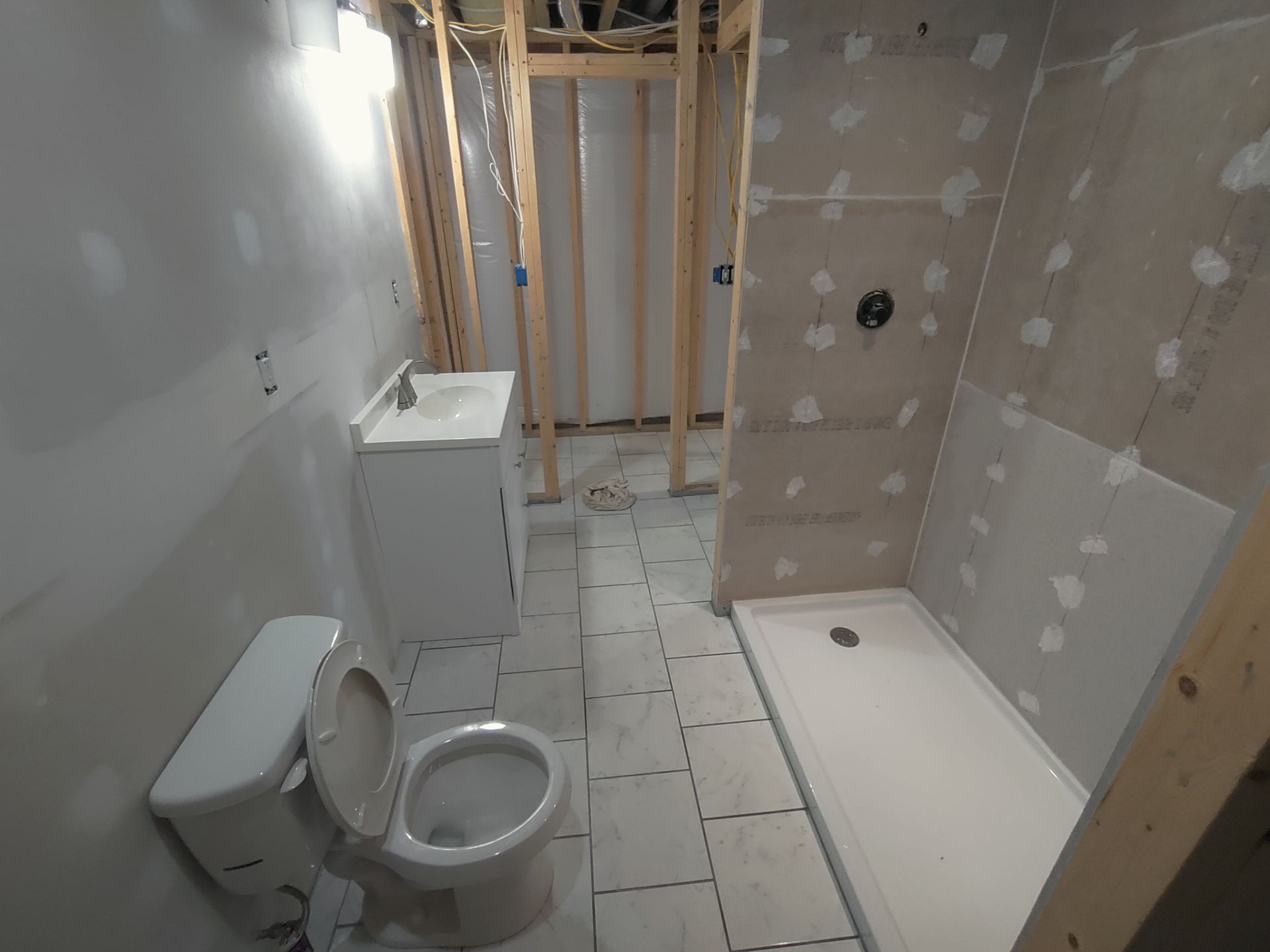 A bathroom under construction with a toilet , sink and shower.