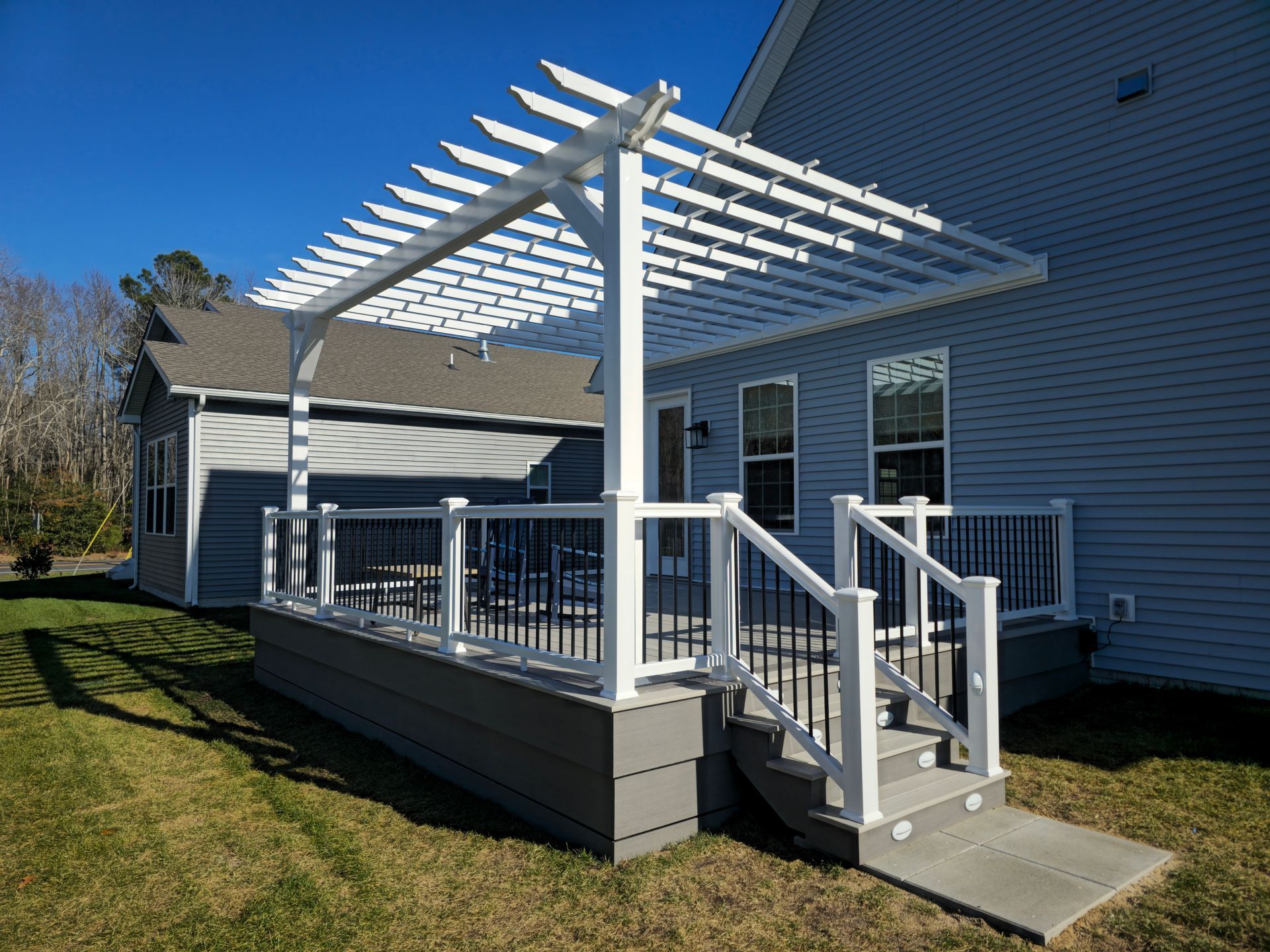 A wooden deck with a white railing is lit up at night.