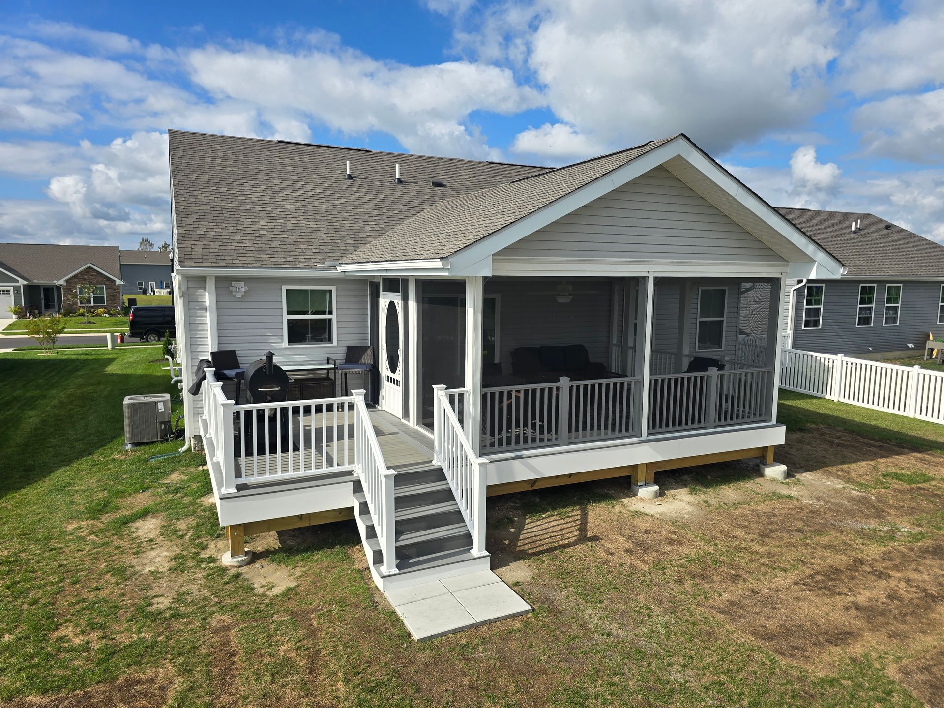 A screened in porch with a blue house in the background