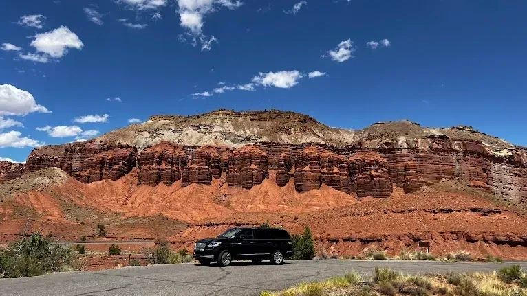 A black suv is parked on the side of a road in front of a mountain.