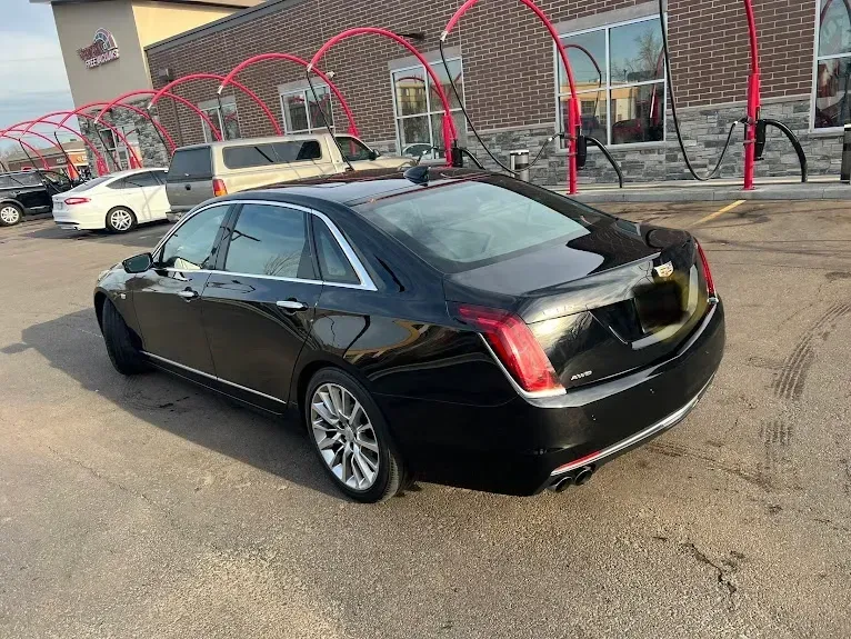 A black cadillac is parked in front of a car wash.