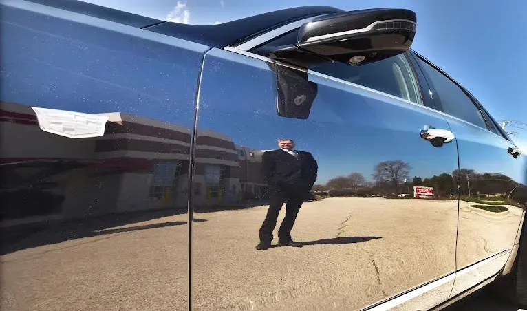 A man is reflected in the door of a car.