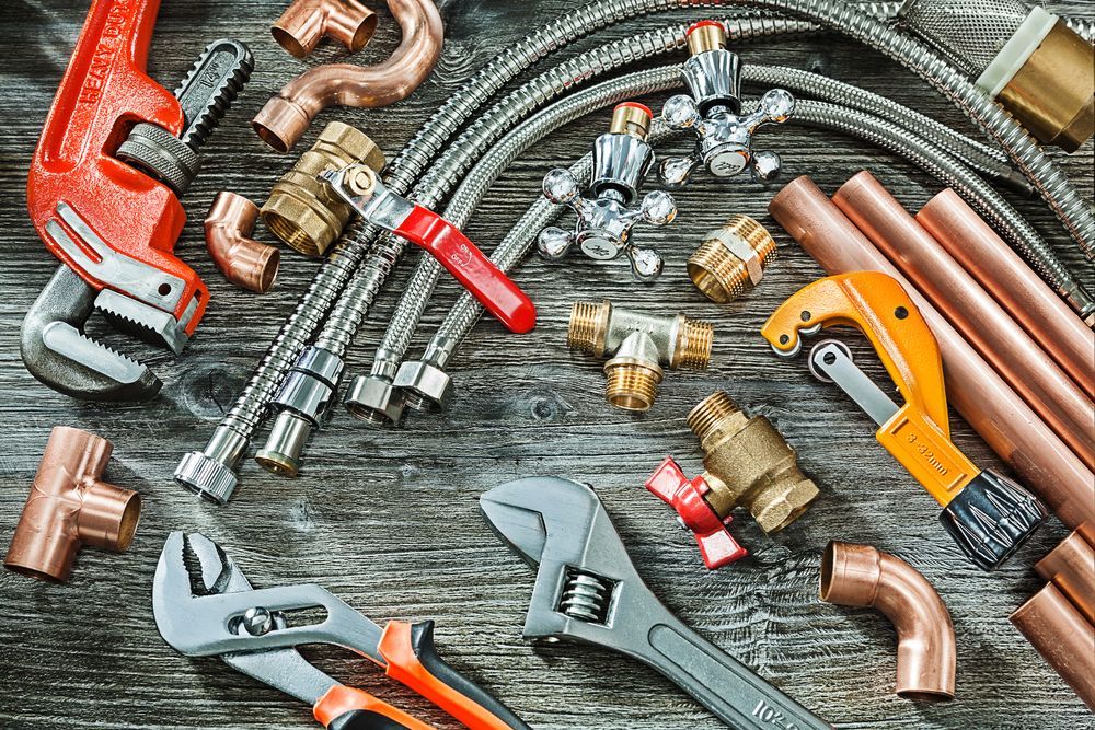 A bunch of plumbing tools and pipes on a wooden table.