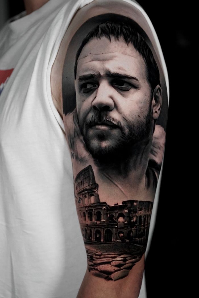 Black and white tattoo of actor Russell Crowe as Maximus with the Colosseum on arm.