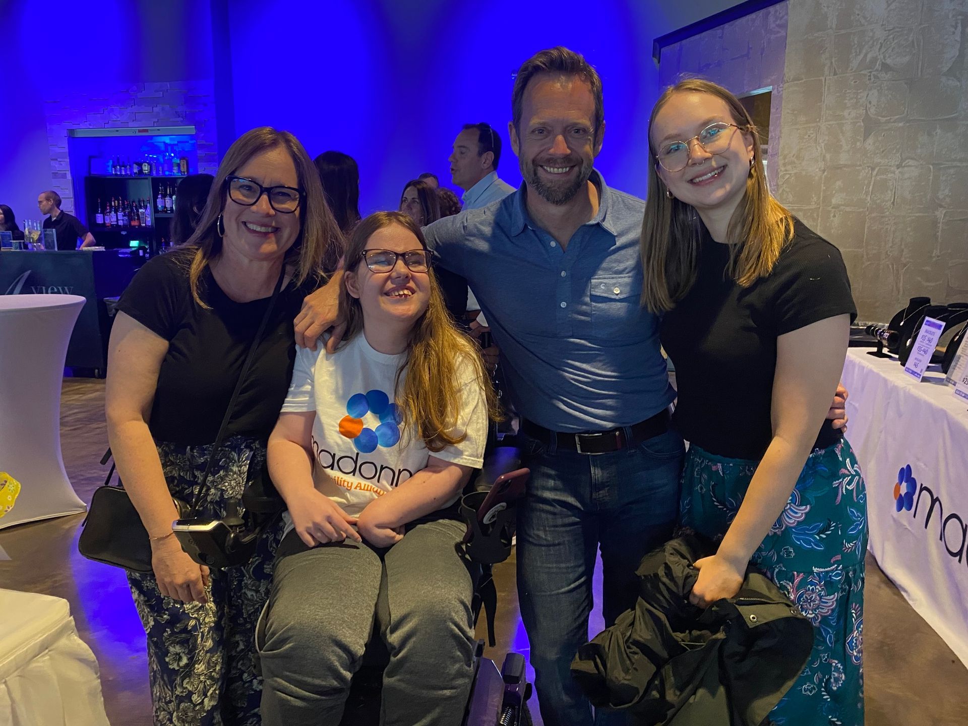 Four smiling people pose for a photo with a blue backdrop.