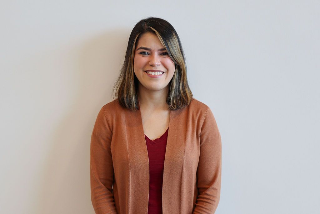 Shadows of horizontal blinds cast across a white wall, creating a striped pattern.