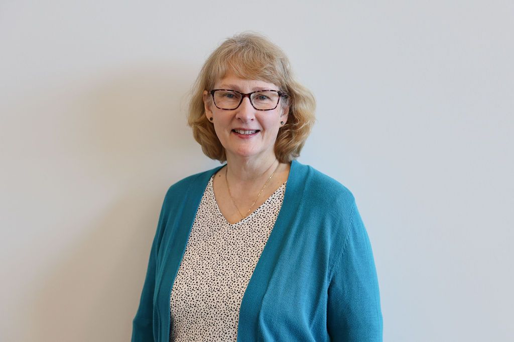 Shadows of horizontal blinds cast across a white wall, creating a striped pattern.