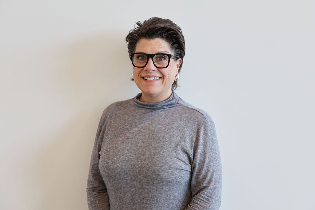 Shadows of horizontal blinds cast across a white wall, creating a striped pattern.