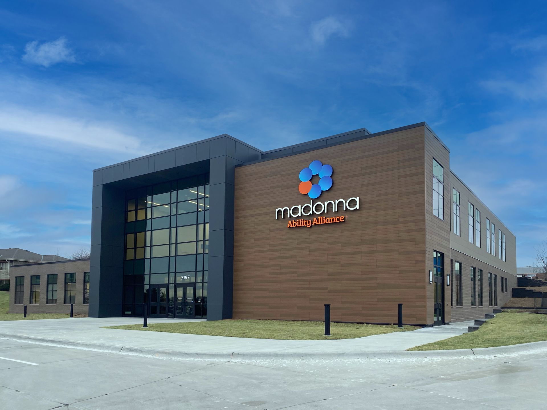 Moderna Center building featuring a large glass entrance, brown siding, and company logo under a blue sky.