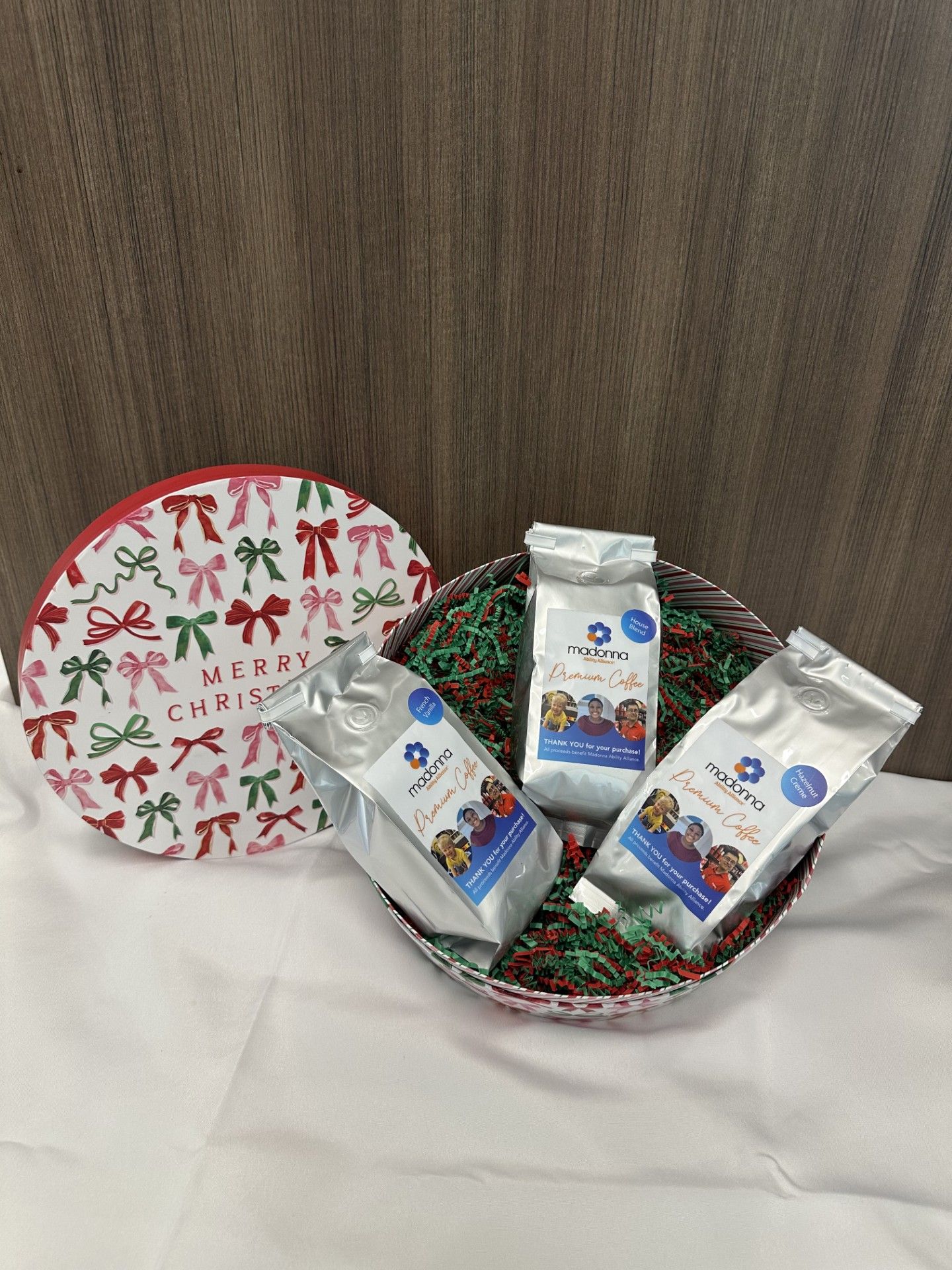 Christmas gift basket with three bags of product, red and green bows on container.