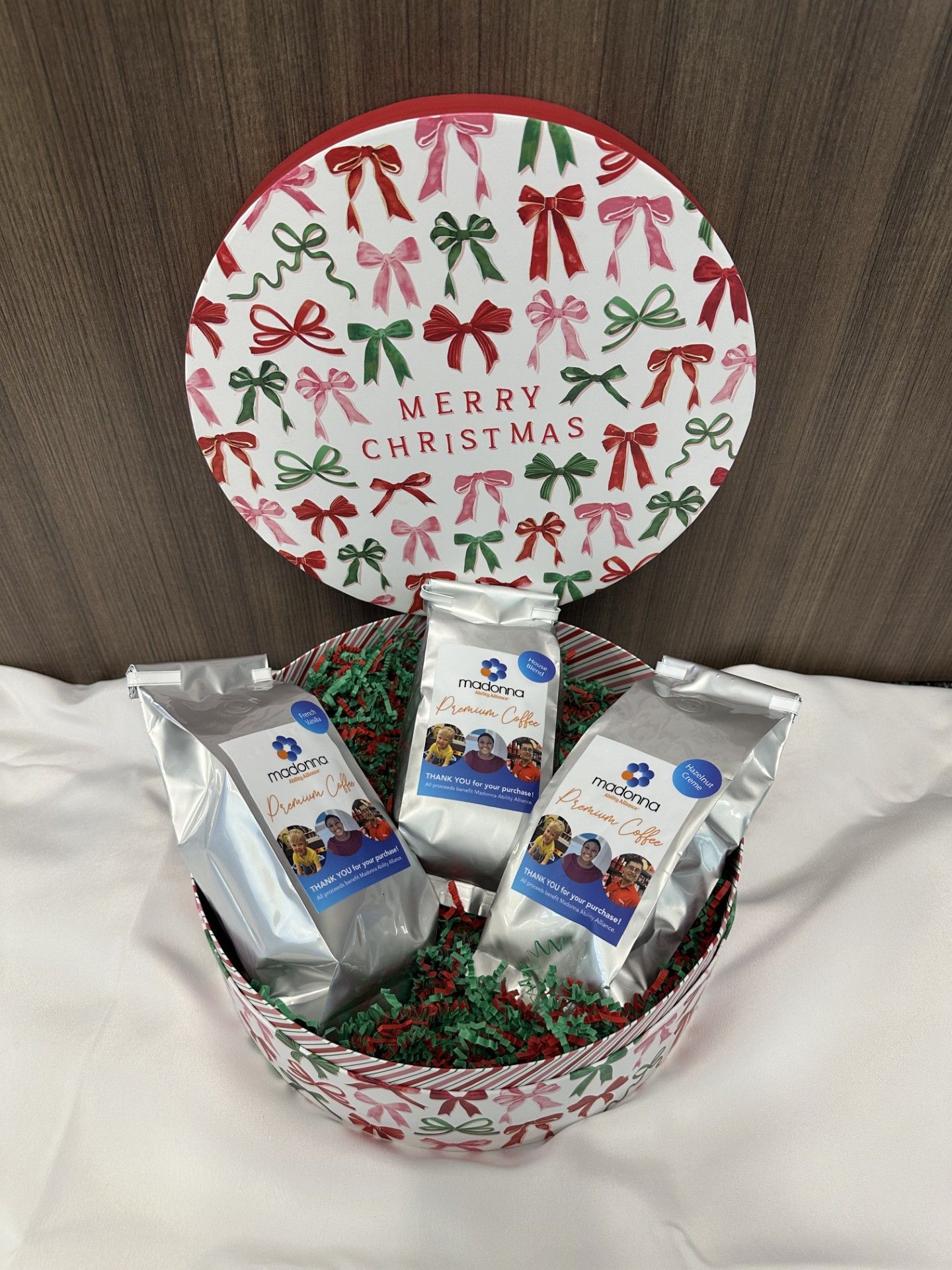 Christmas gift basket with three bags of product, red and green bows on container.